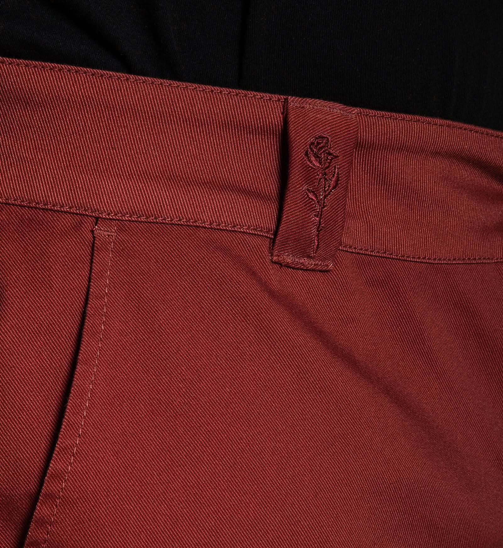 Close-up of a maroon pants pocket with a brand logo.