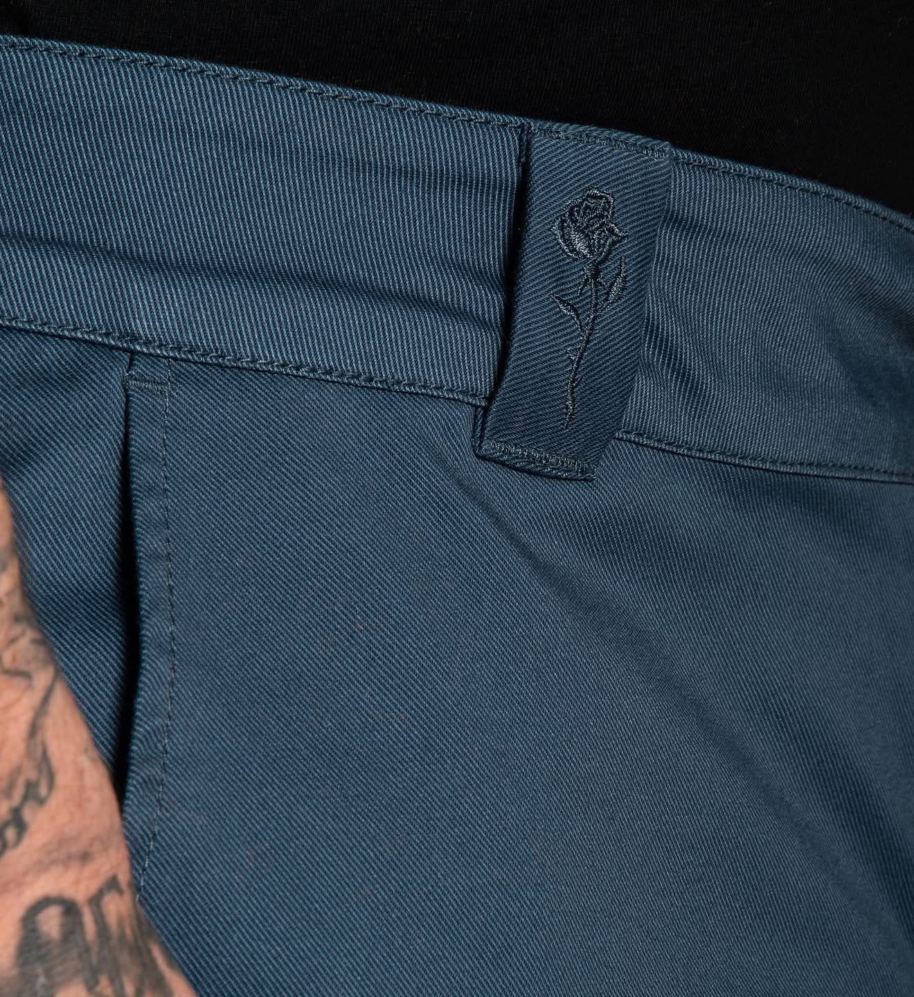 Close-up of a blue pants waistband with a brand logo on a black background