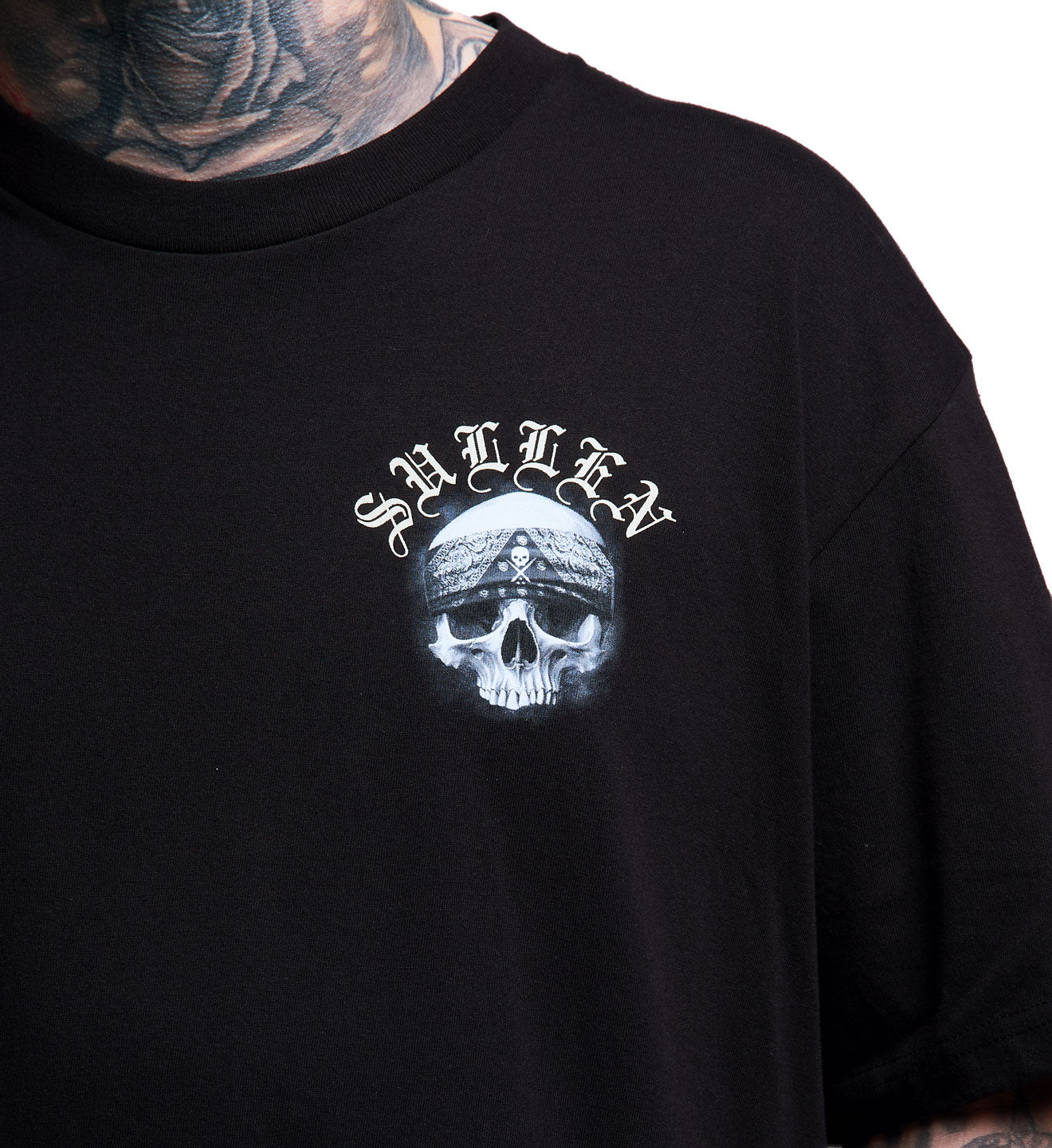 Black t-shirt with skull and text design worn by a person with tattoos.