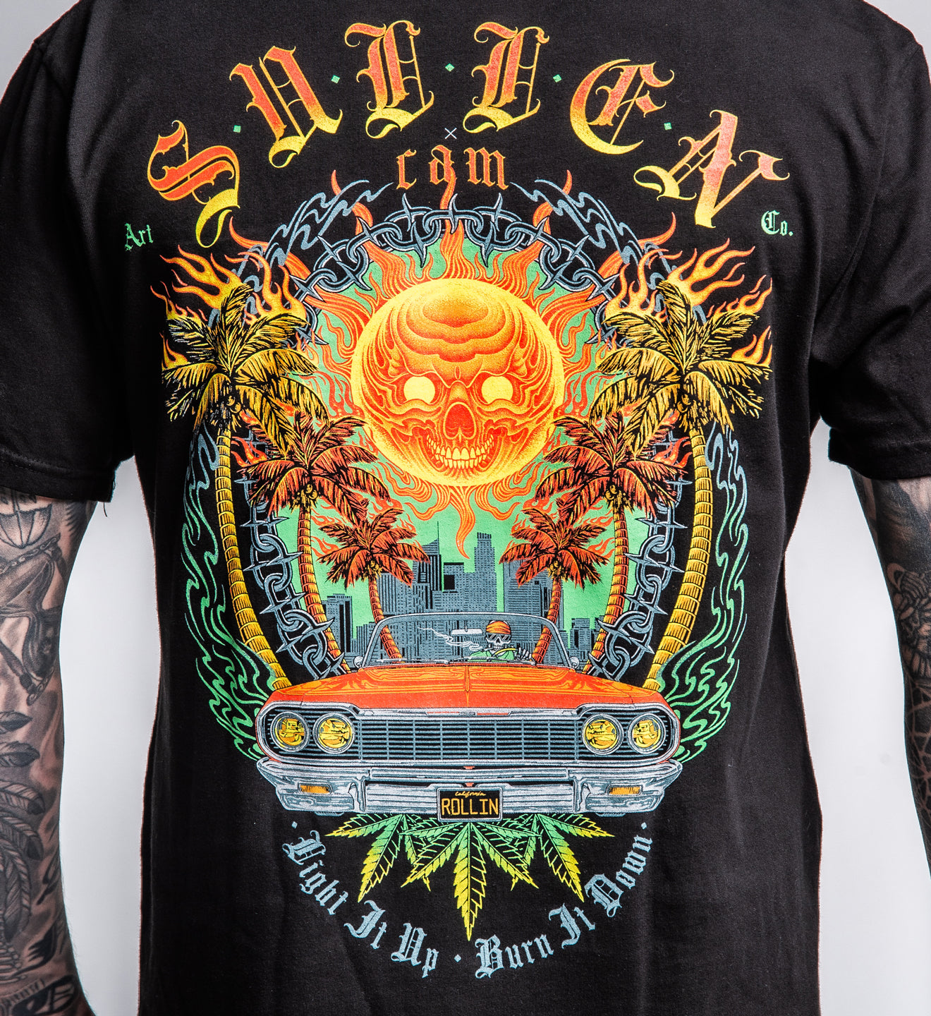 Black t-shirt with a colorful graphic design featuring a sun, palm trees, and a car.