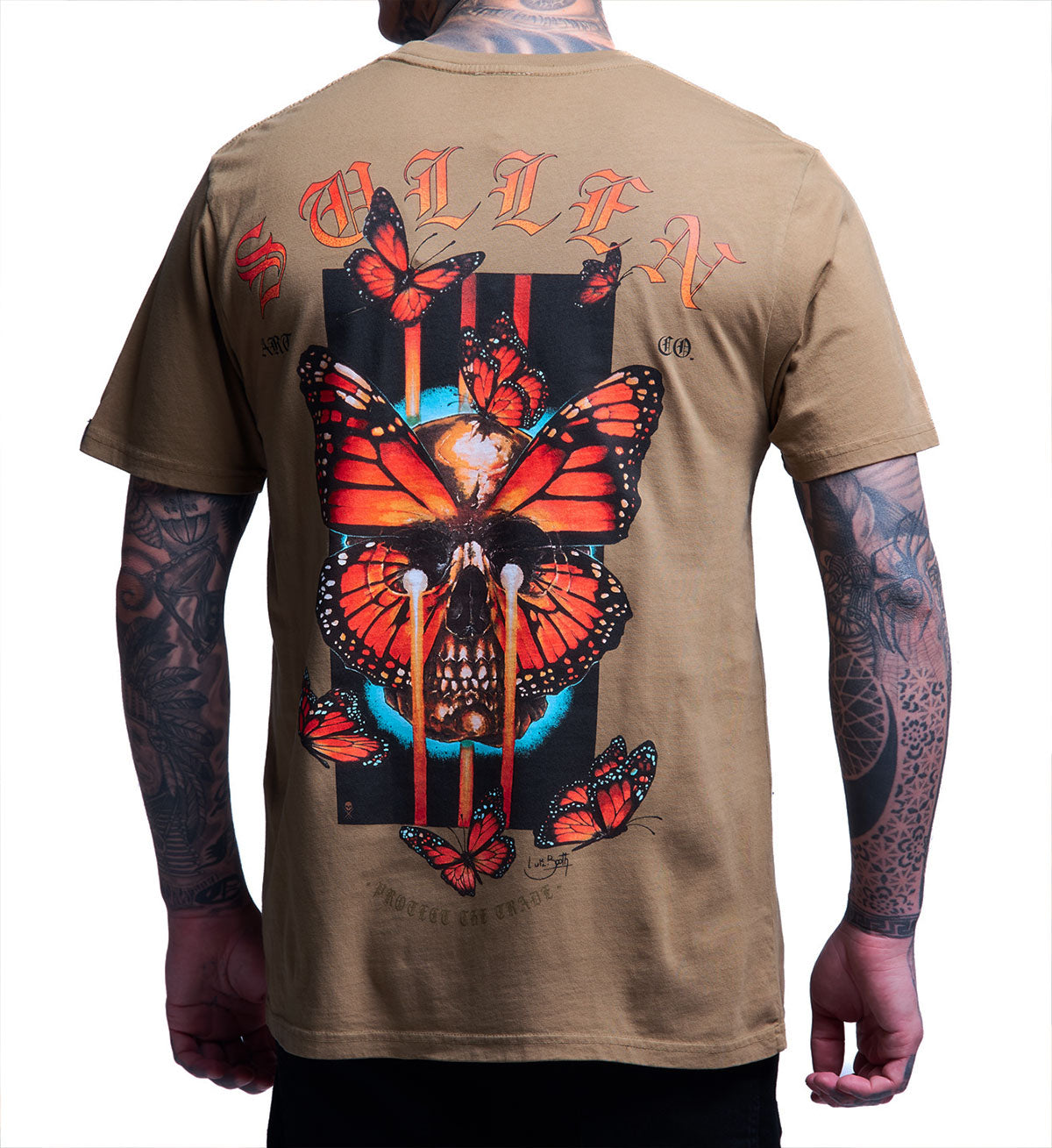 Beige t-shirt with butterfly and skull design on the back, worn by a person.