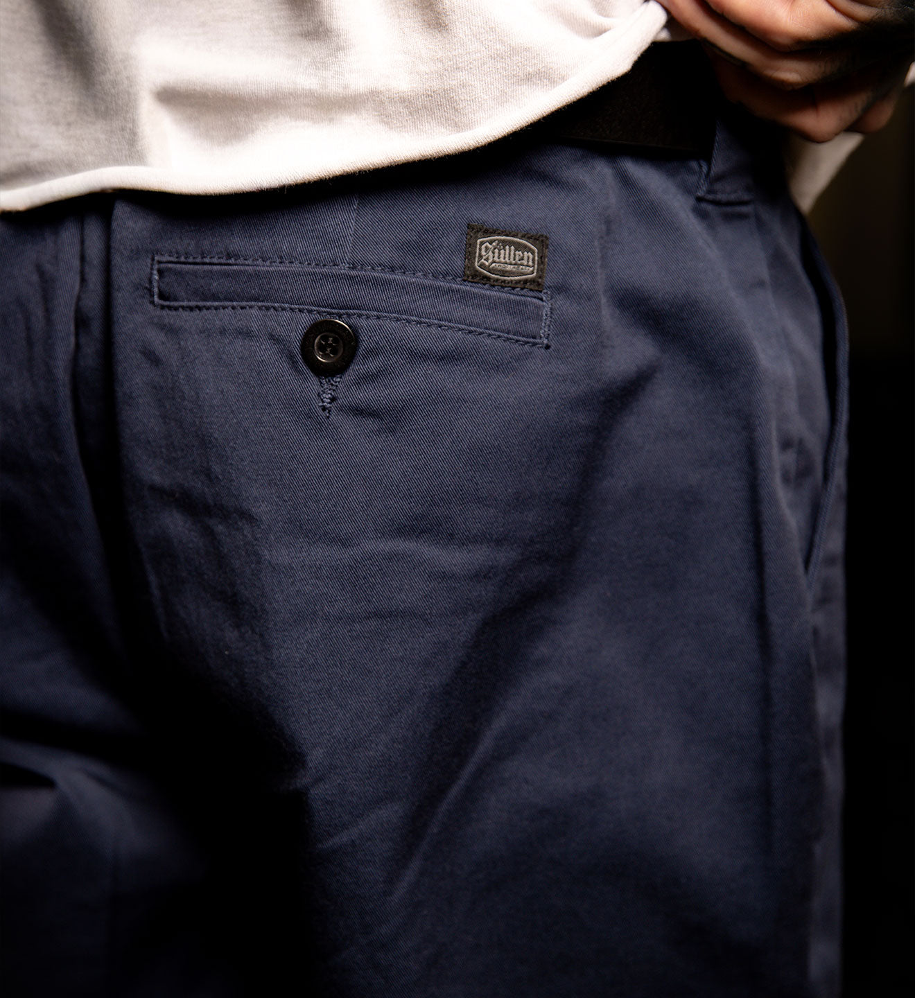 Navy pants with a brand logo on the pocket against a dark background