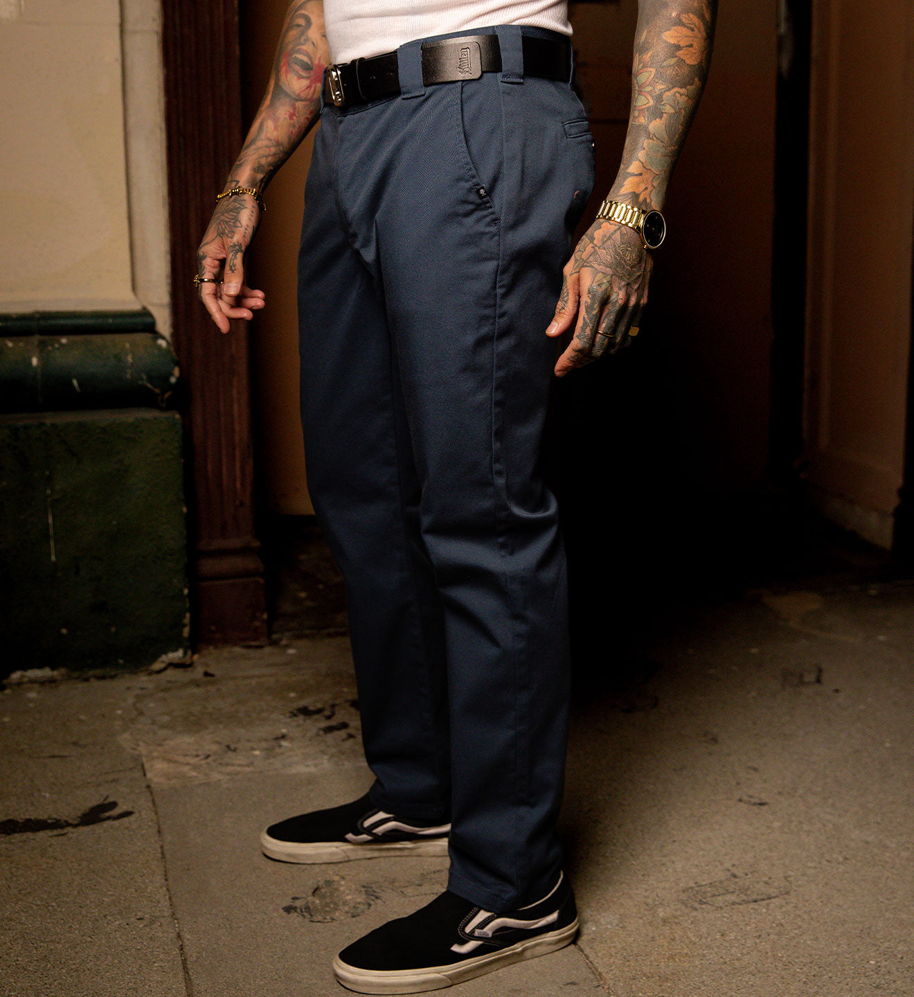 Person wearing navy pants and black sneakers in an urban setting