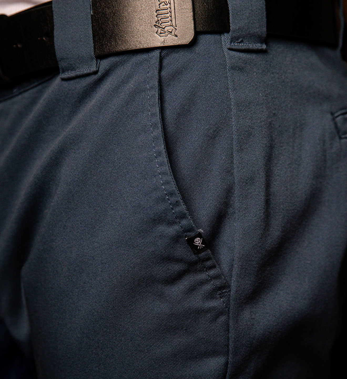 Close-up of a dark blue shirt with a belt and buckle.