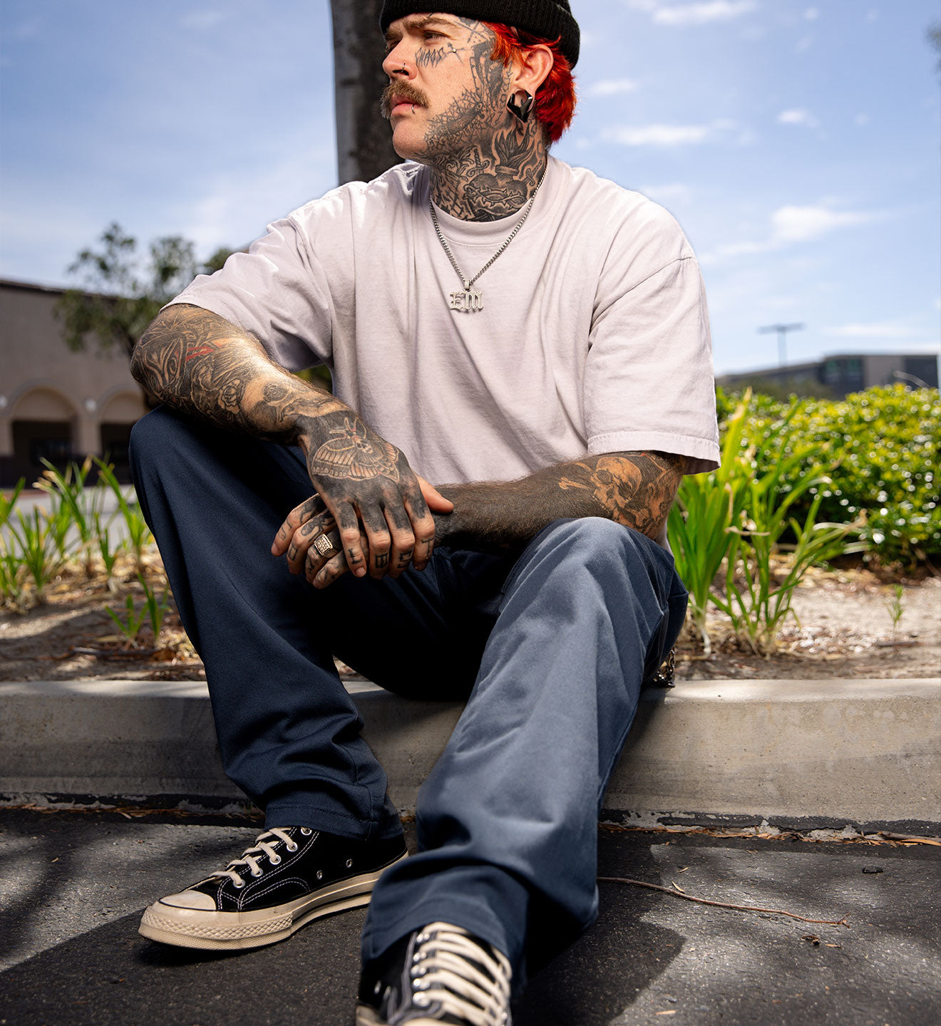 Person with tattoos sitting on a ledge outdoors