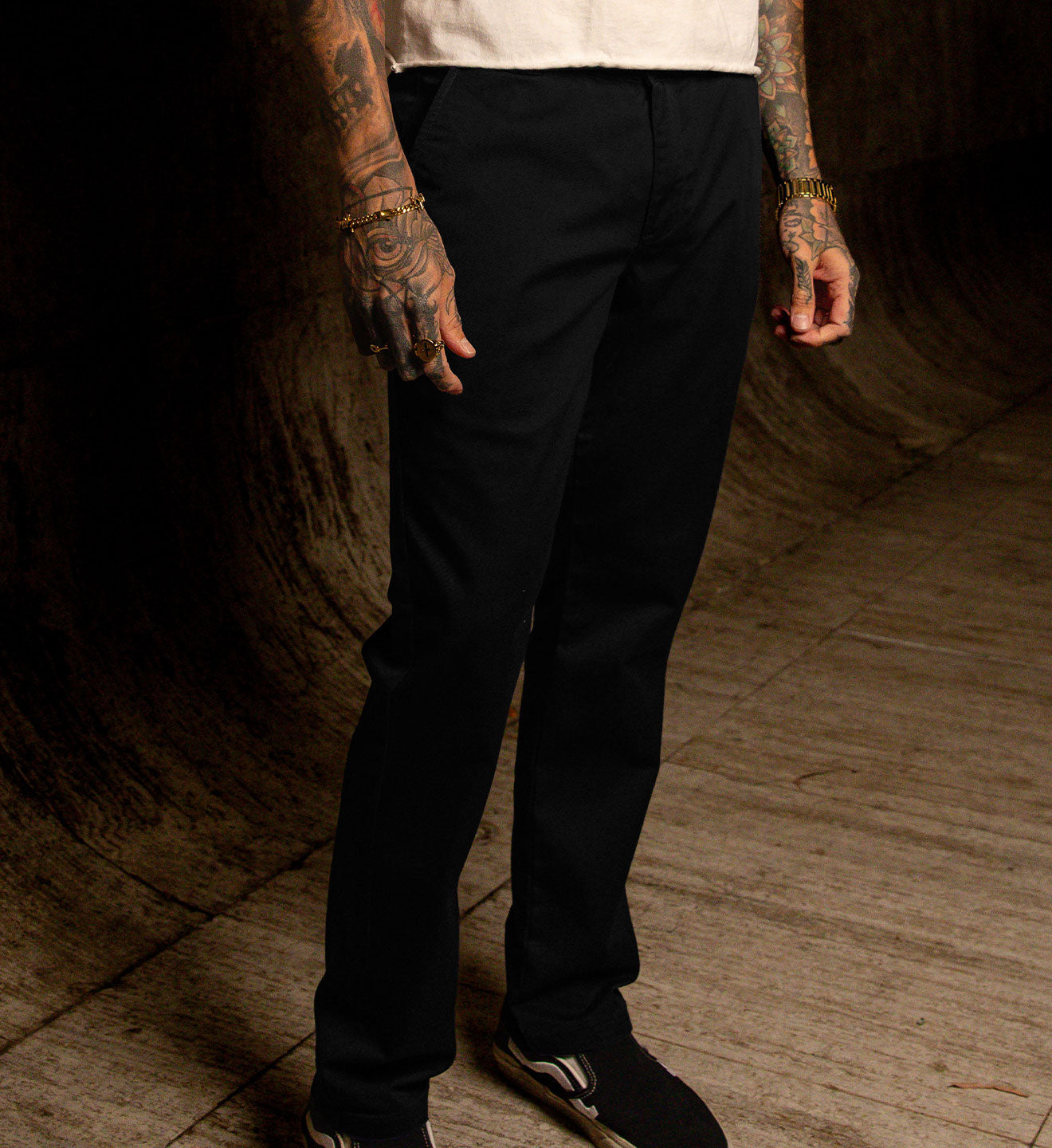 Person wearing black pants standing in a dimly lit room with wooden floor.