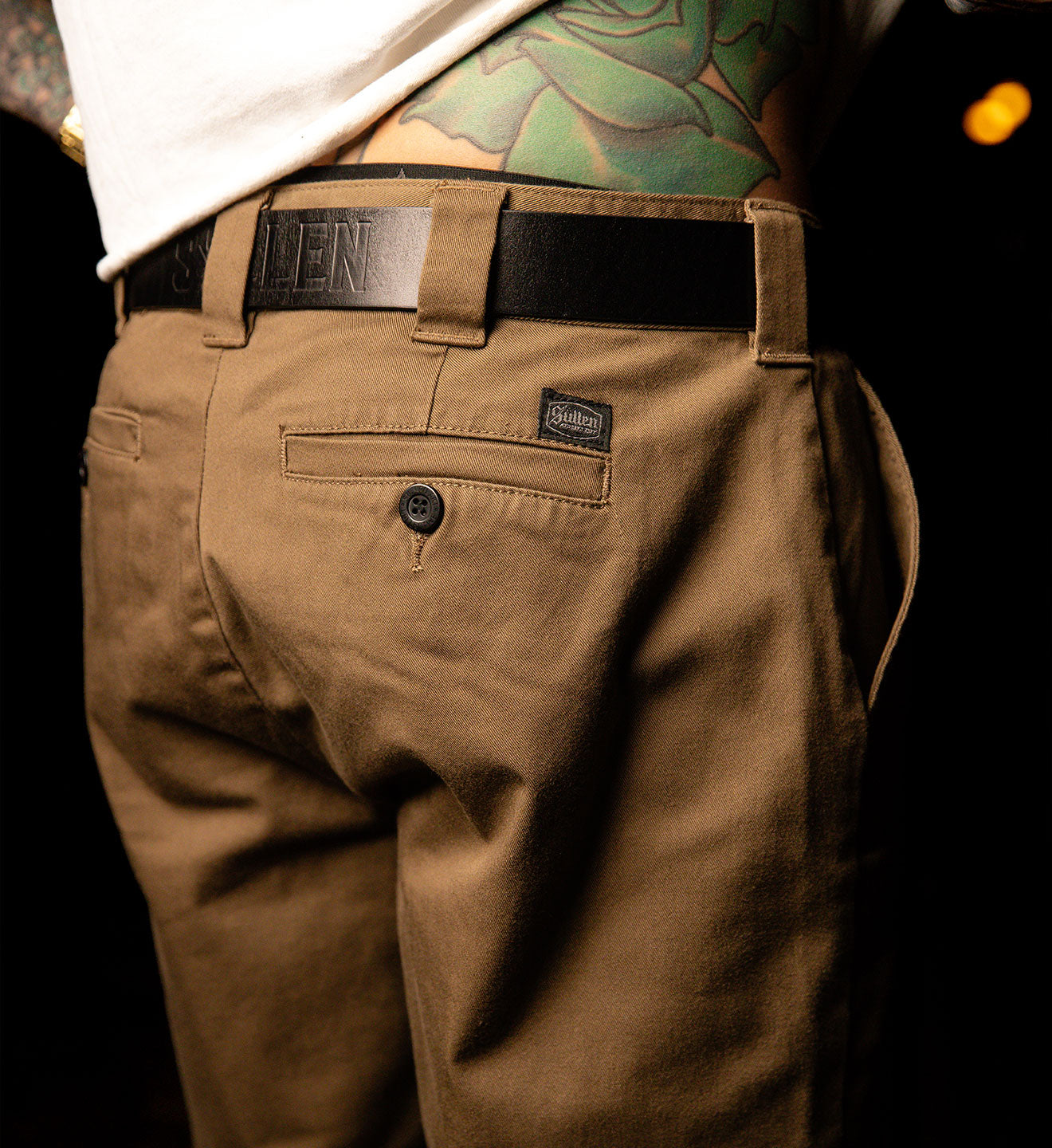 Brown pants with a visible brand label on a dark background