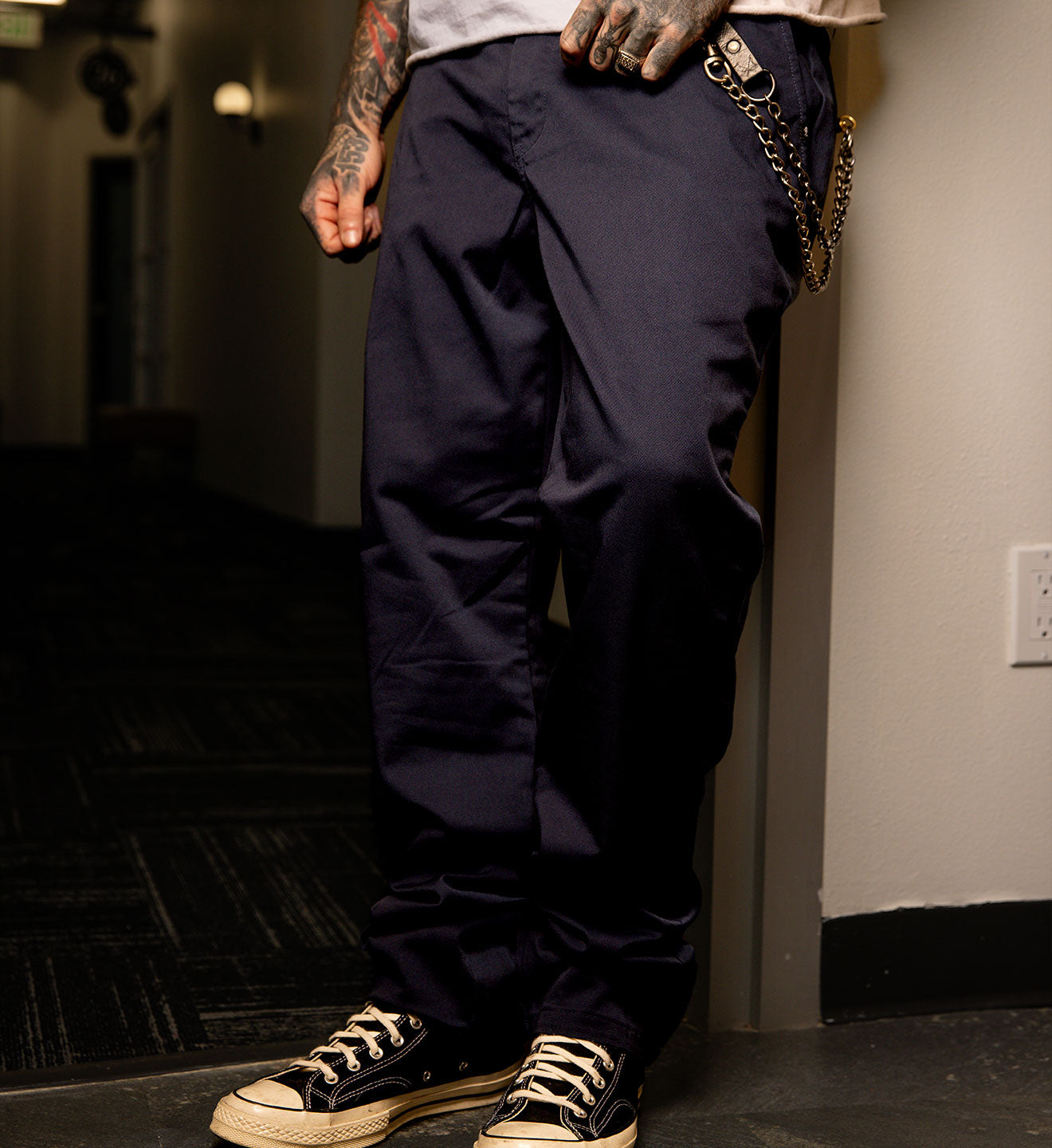 Person wearing navy blue pants and black sneakers in a dimly lit room.