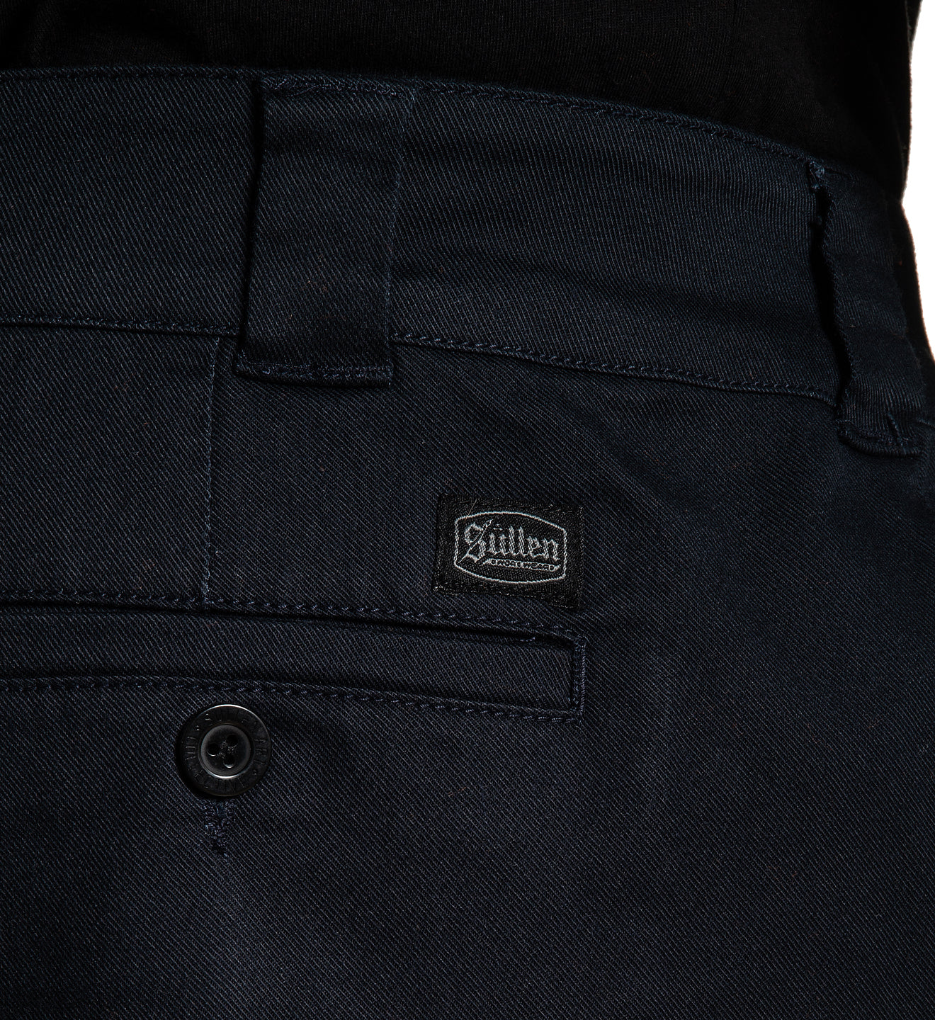 Close-up of black pants with a brand logo on the pocket
