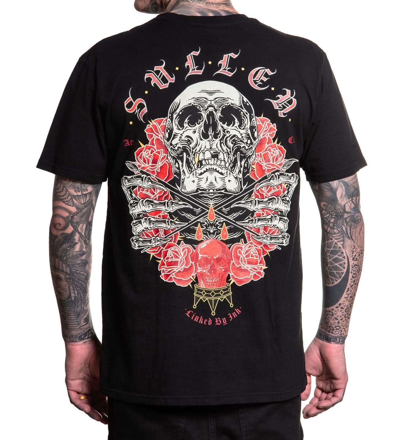 Black t-shirt with a skull and roses design on the back, worn by a person with tattoos.
