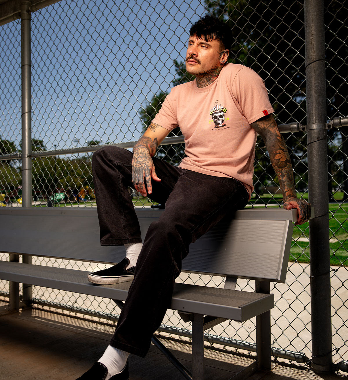 Man sitting on a bench wearing a pink t-shirt with a graphic design.