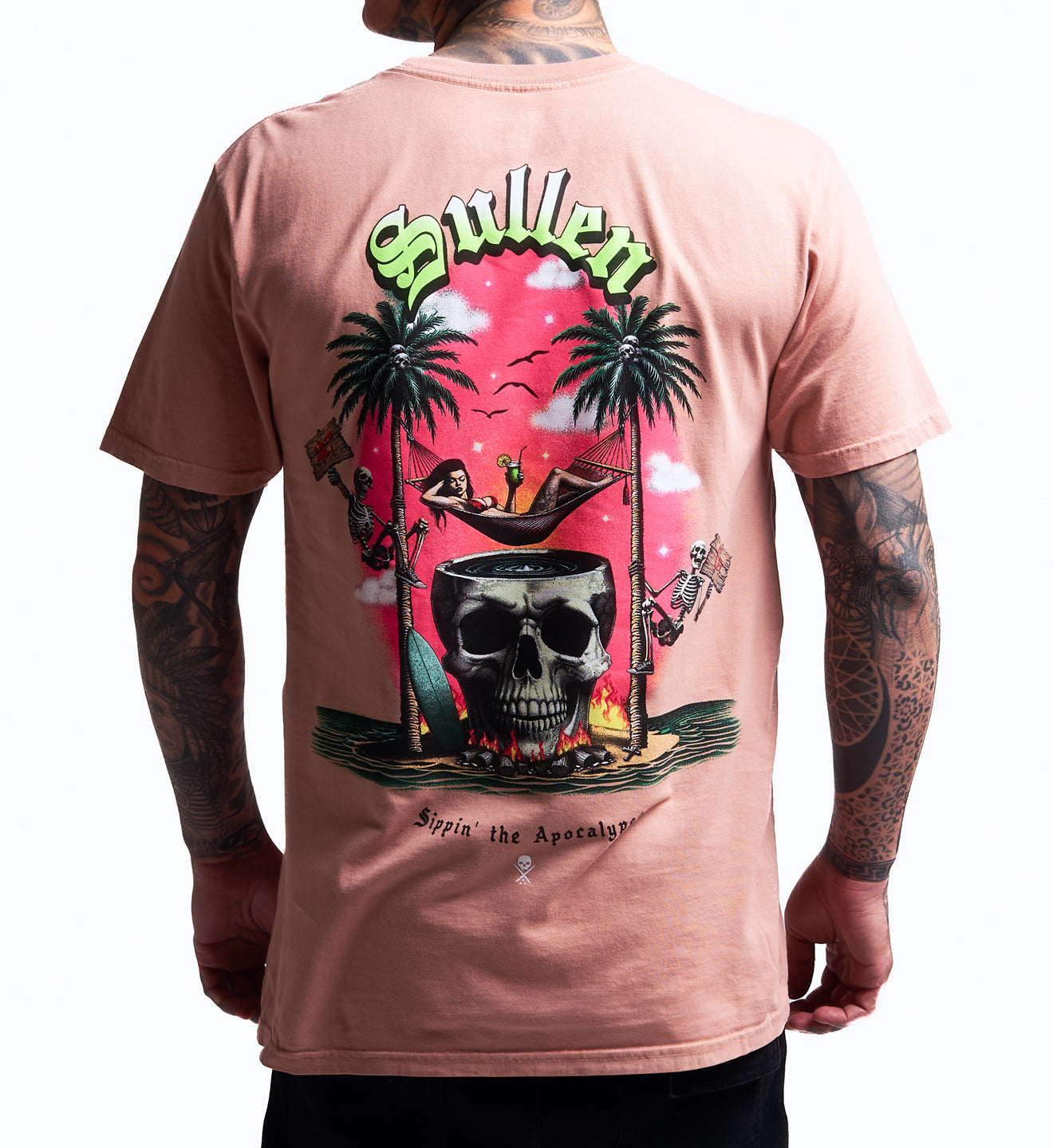 Person wearing a pink t-shirt with a colorful graphic design on the back, featuring palm trees, a skull, and text.