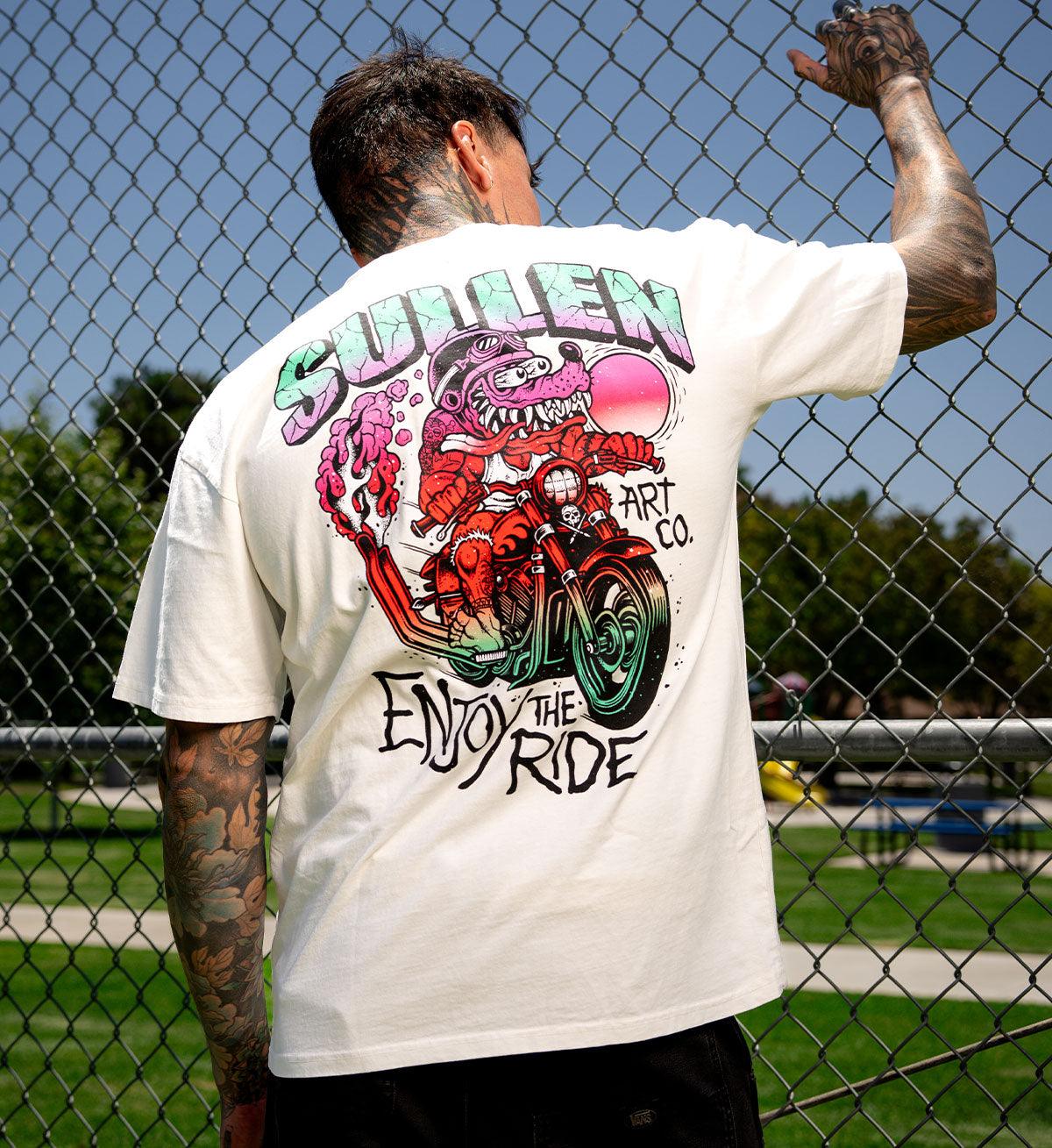 Person wearing a white t-shirt with a colorful graphic design in an outdoor setting.