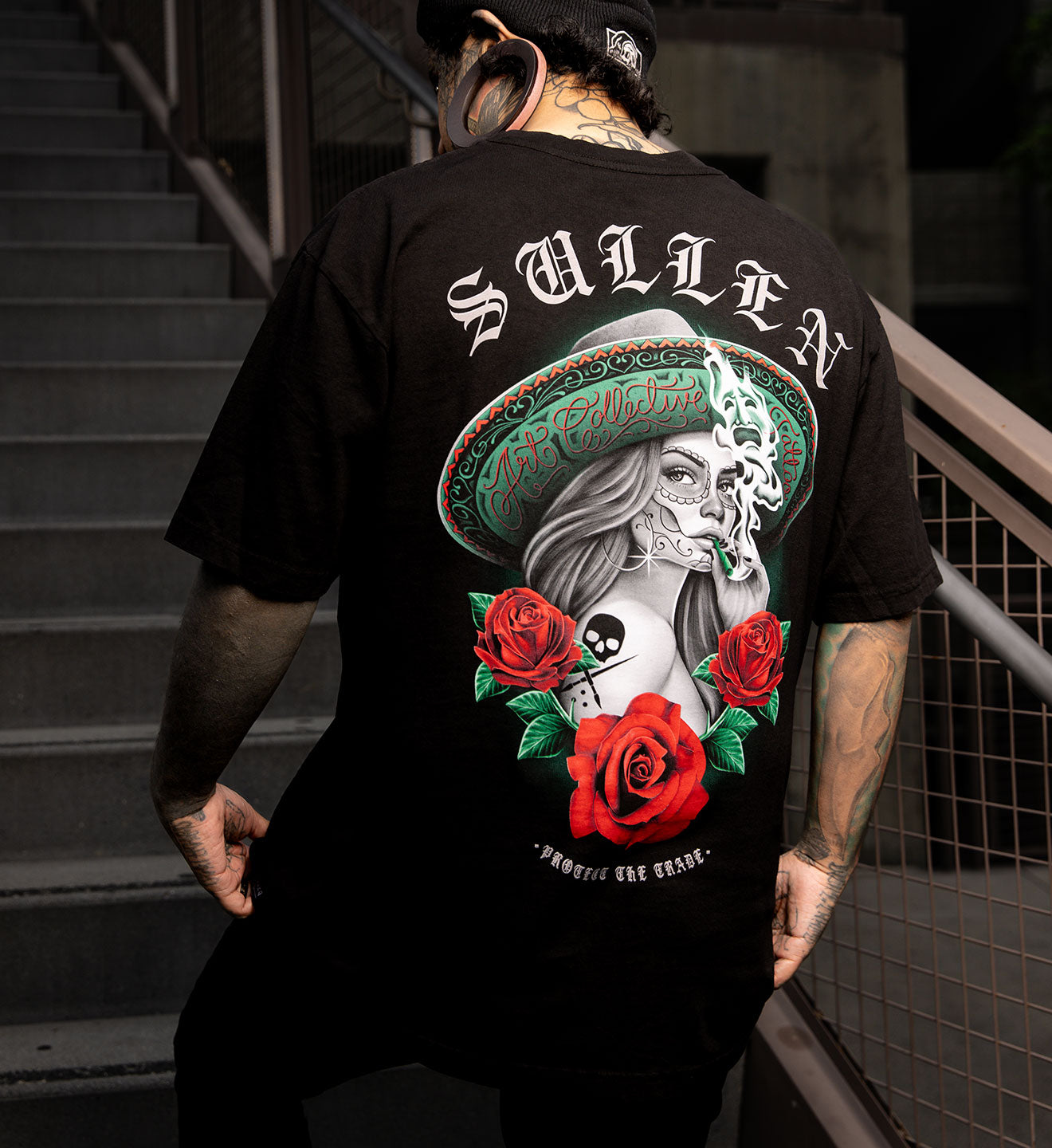 Person wearing a black t-shirt with a colorful graphic design on the back, standing on stairs.