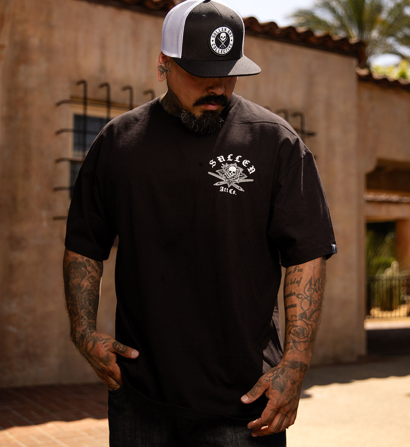 Person wearing a black t-shirt with a graphic design on the back, standing outdoors.