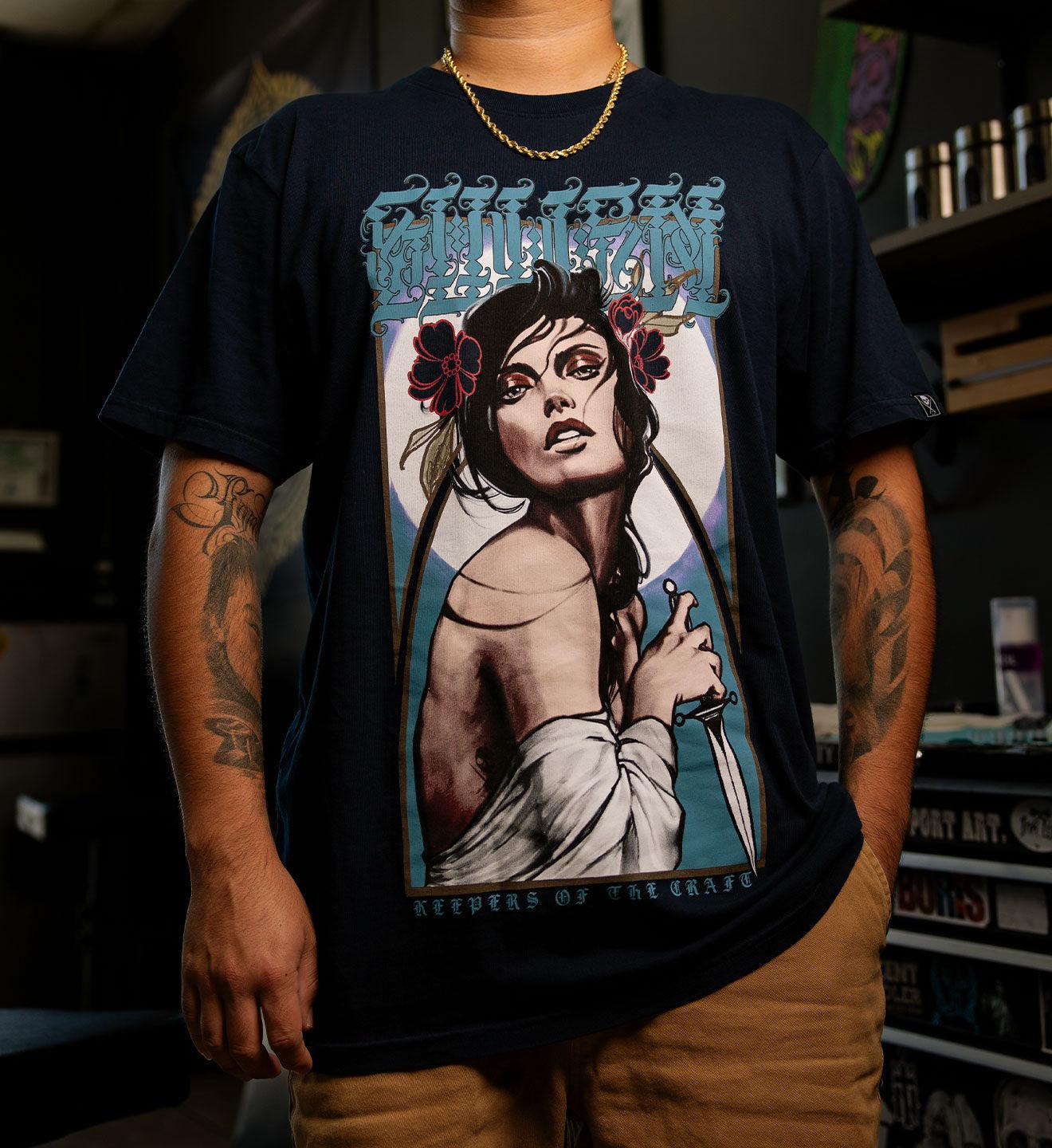 Person wearing a black t-shirt with a graphic design of a woman holding a gun and text.