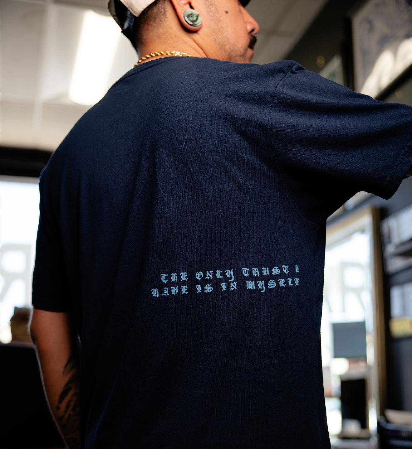 Person wearing a navy blue t-shirt with text on the back in an indoor setting