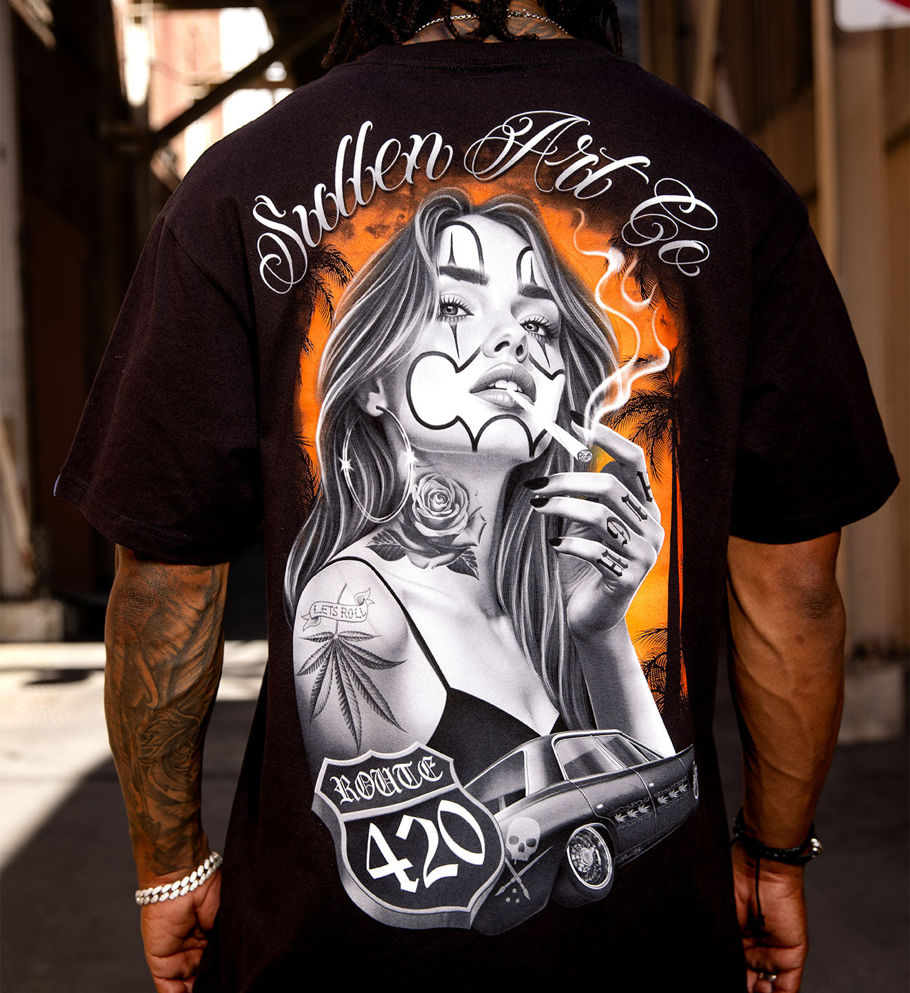 Person wearing a black t-shirt with a graphic design of a woman smoking a cigarette, Route 420 logo, and 'Stolen Art' text.