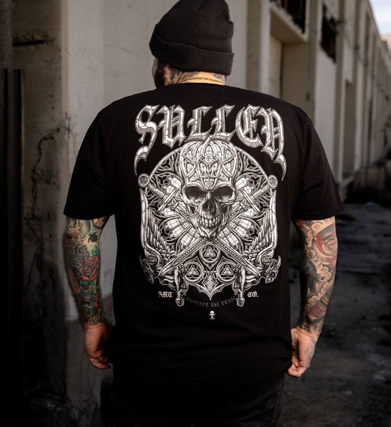 Person wearing a black t-shirt with a detailed skull design and 'Sullen' branding.