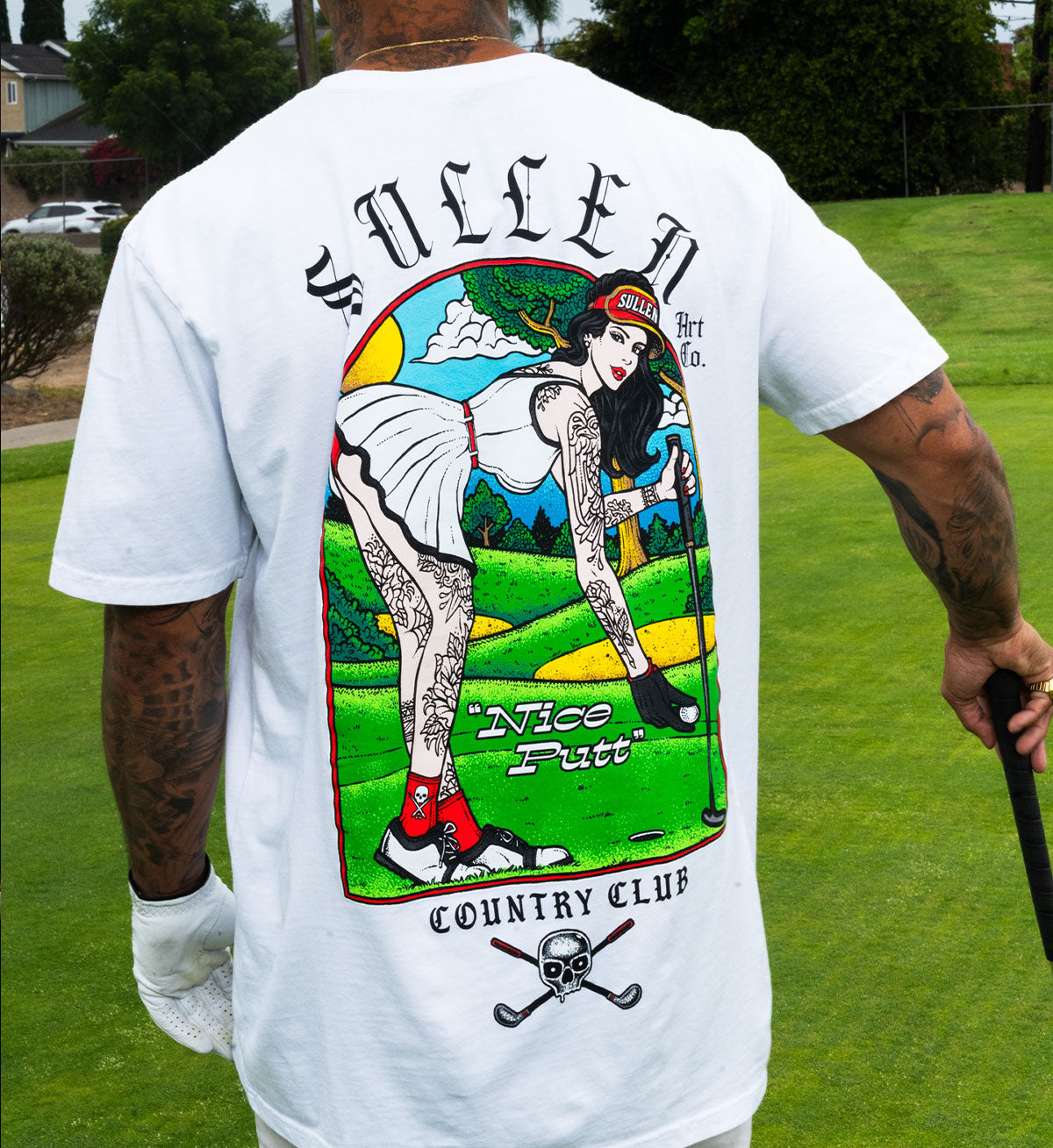Person wearing a white t-shirt with a colorful graphic design on the back, featuring a woman in a golf outfit.