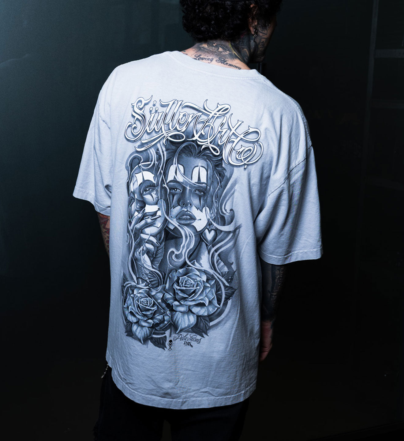 Person wearing a gray t-shirt with a graphic design on the back against a black background
