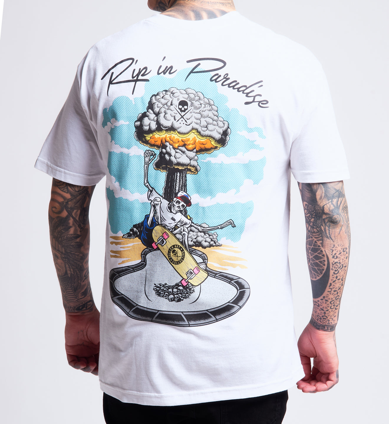 White t-shirt with a graphic design of a skeleton playing guitar and an explosion, with 'Rip in Paradise' text.