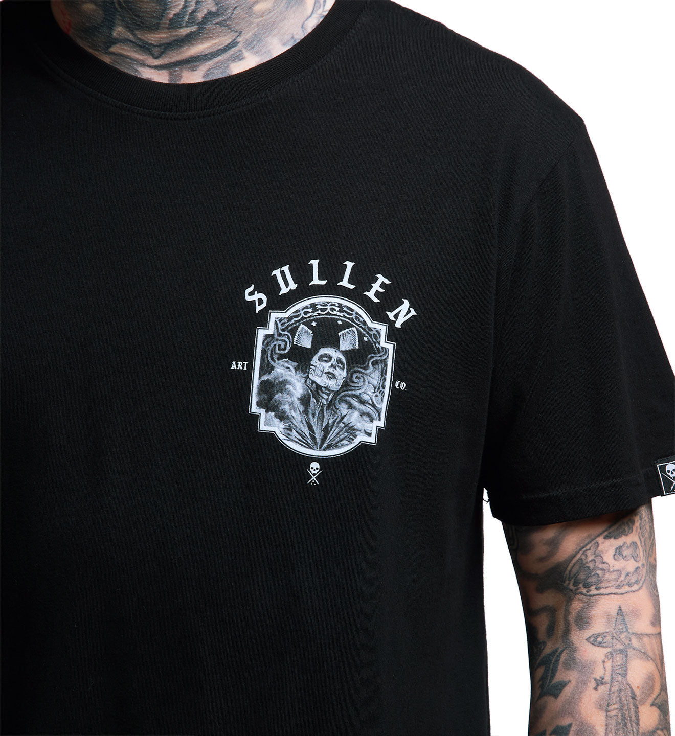 Black t-shirt with a graphic design and 'Sullen' branding on a tattooed arm.