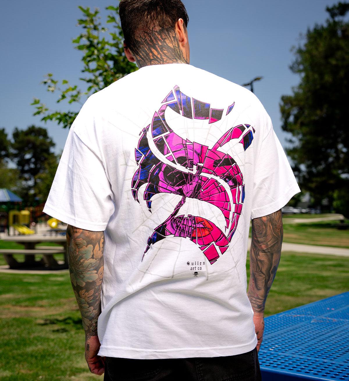 Person wearing a white t-shirt with a colorful graphic on the back in an outdoor setting.