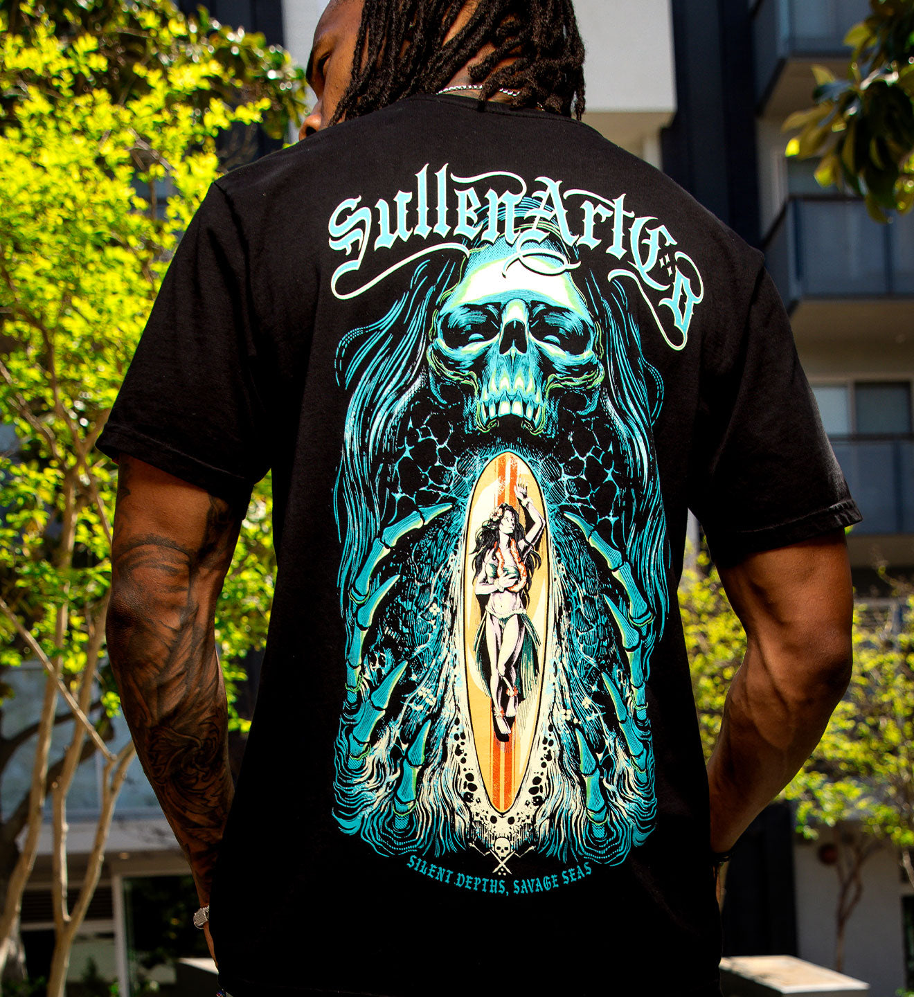 Person wearing a black t-shirt with a colorful graphic design on the back, featuring a skull and abstract elements.