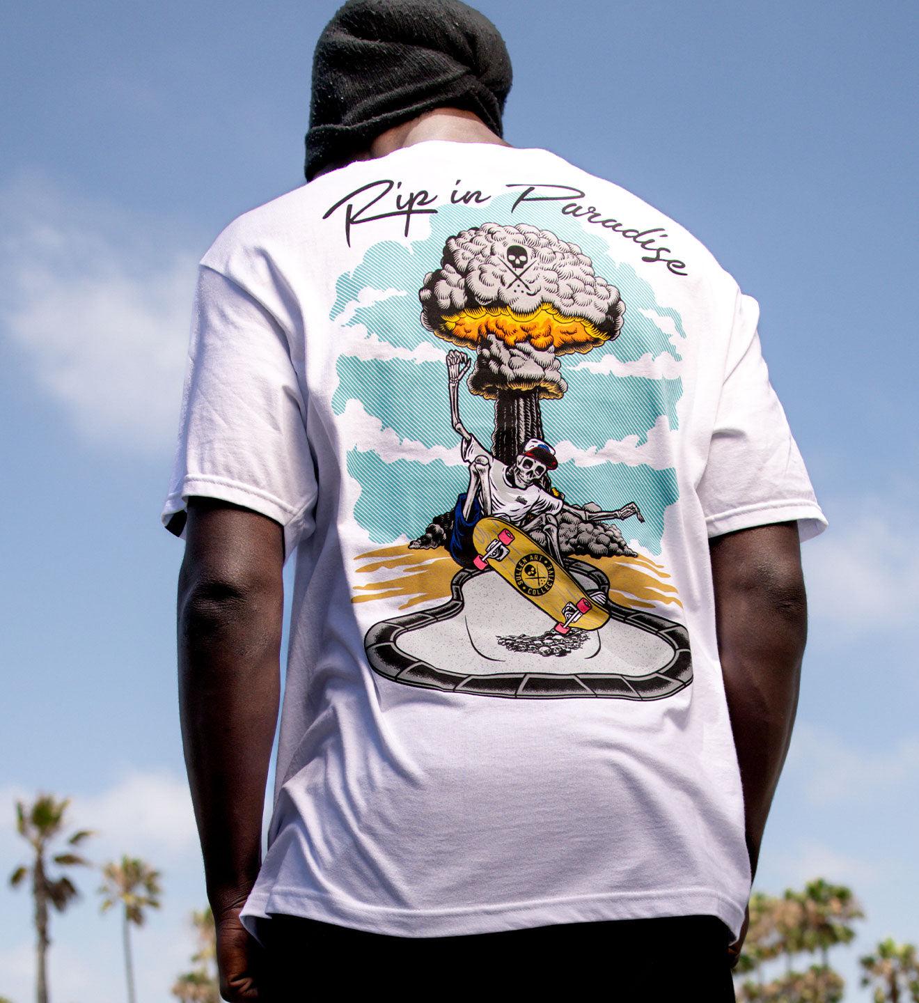 Person wearing a white t-shirt with a graphic design on the back, set against a clear blue sky.