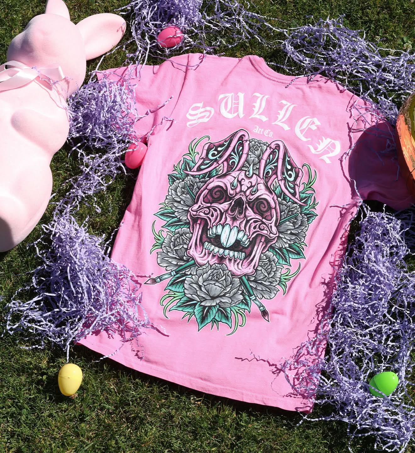 Pink t-shirt with a skull design on grass with decorative elements