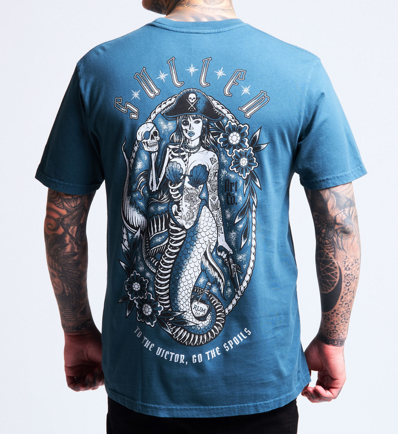 Blue t-shirt with a skeleton mermaid design on the back, worn by a person.