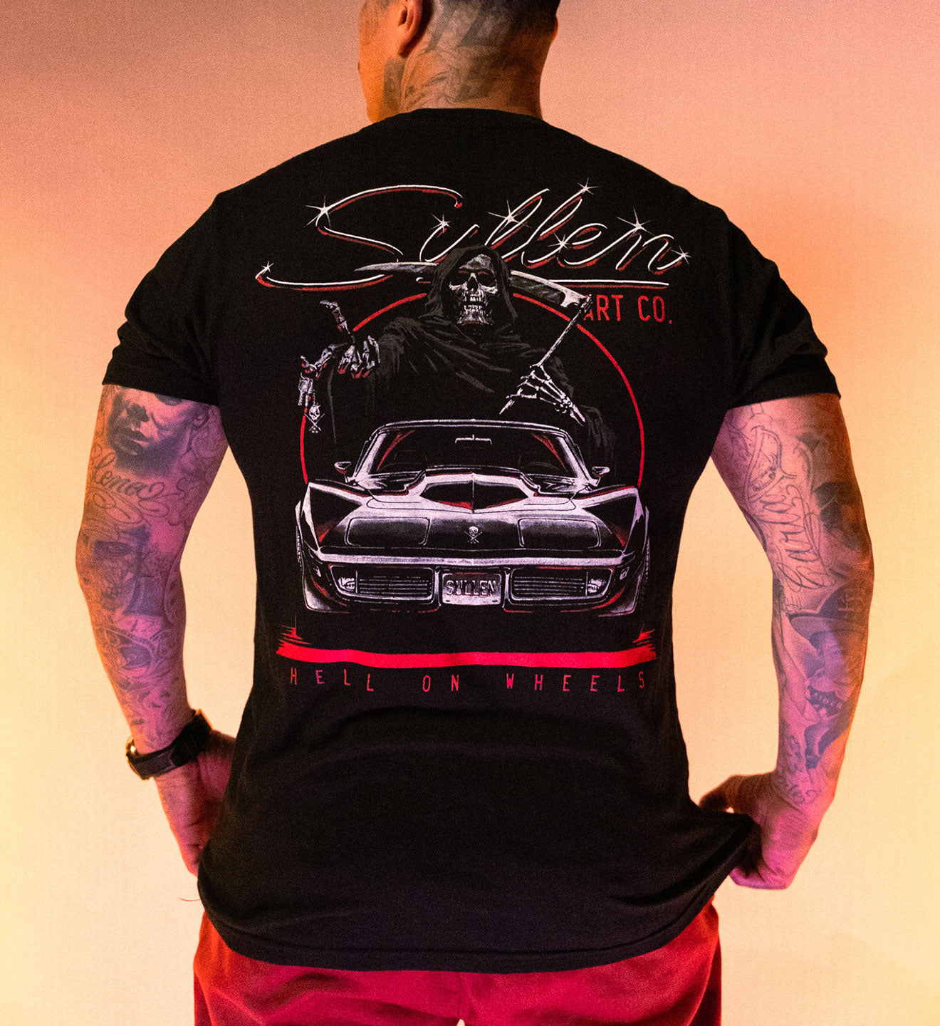 Person wearing a black t-shirt with a graphic design on the back, set against a warm gradient background.