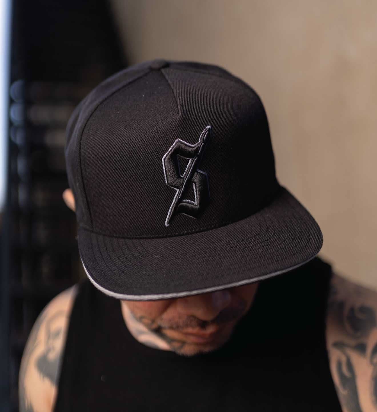 Person wearing a black cap with a logo, blurred background