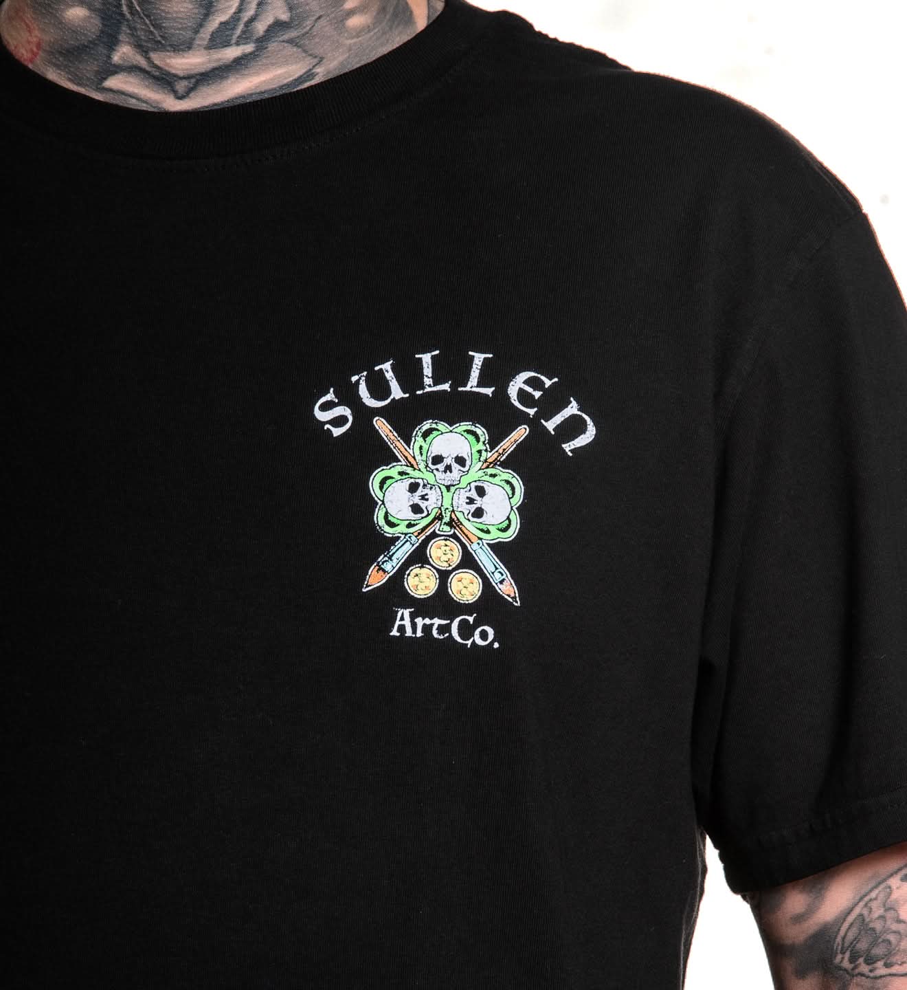 Black t-shirt with Sullen Art Co logo featuring a skull and paintbrushes on a white background.
