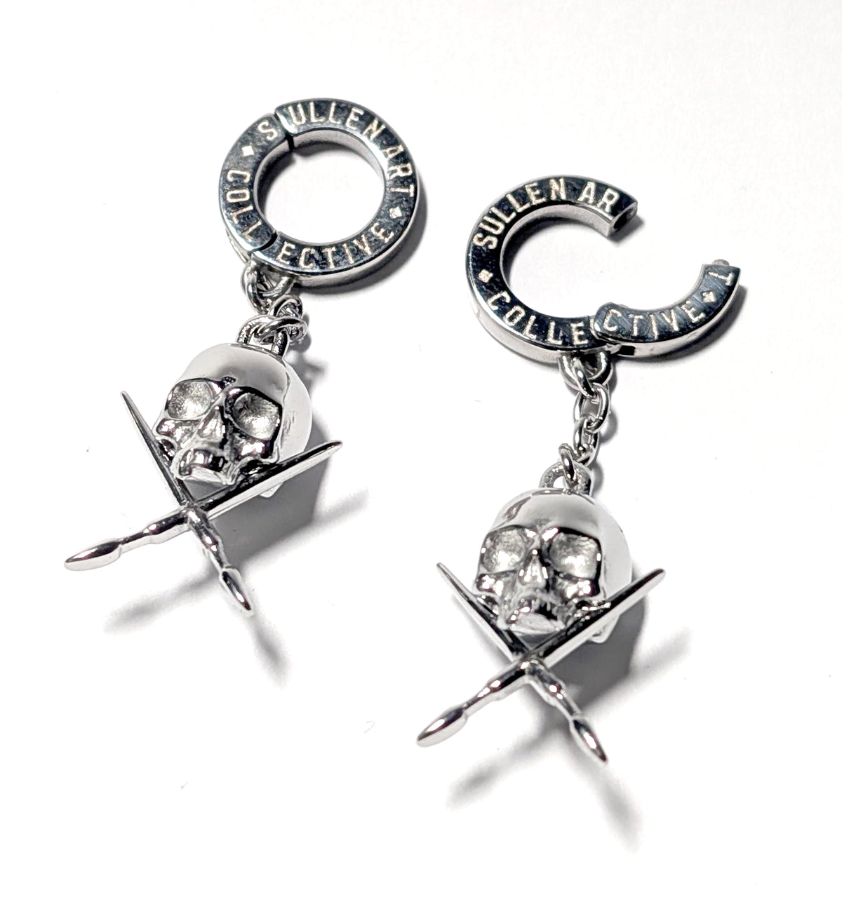 Pair of earrings with skull and crossbones design on a white background