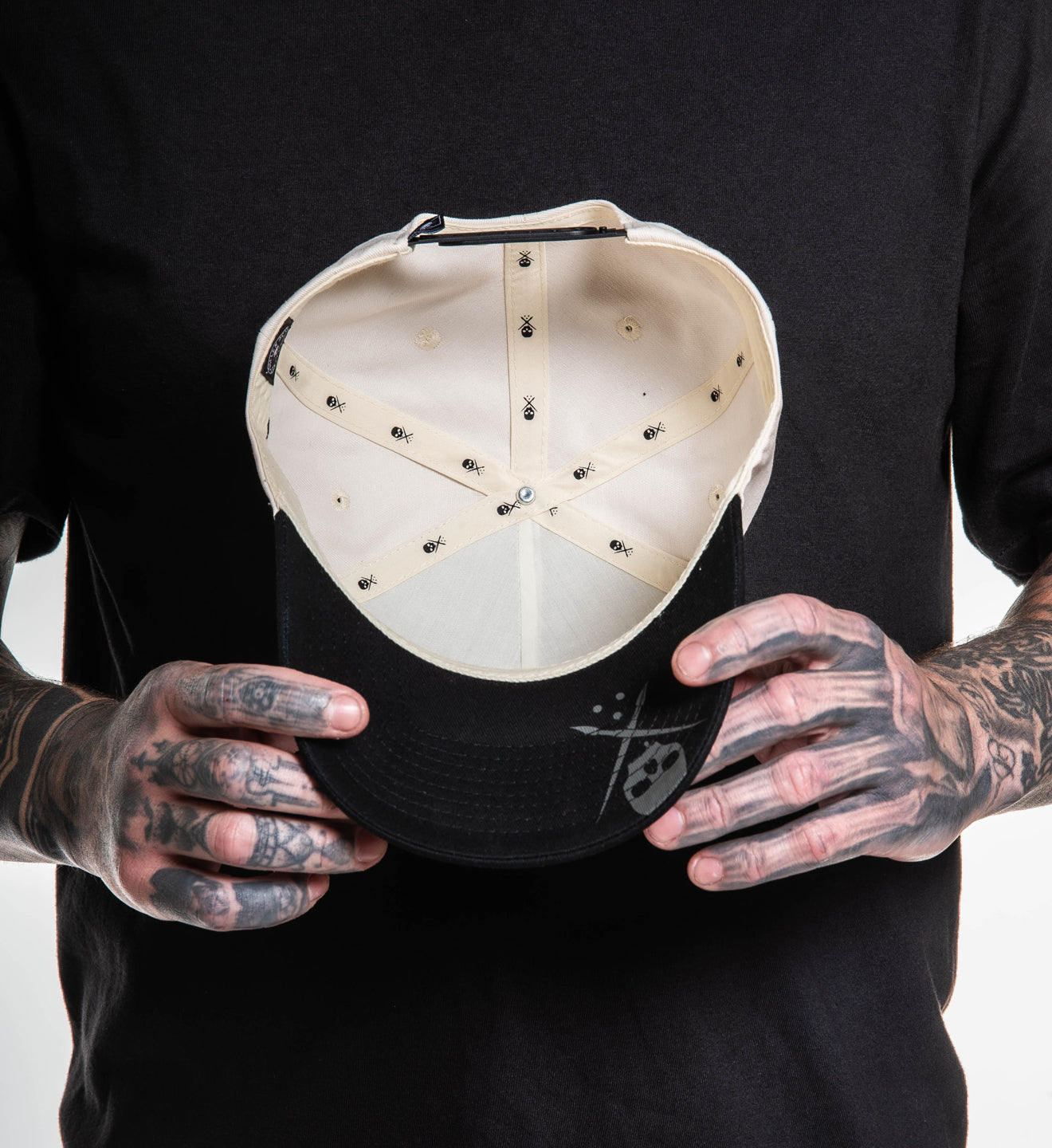 Person holding a black cap with a white interior against a black background