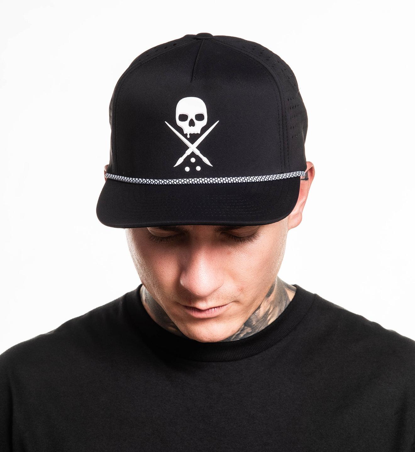 Person wearing a black cap with a skull and crossbones design on a white background
