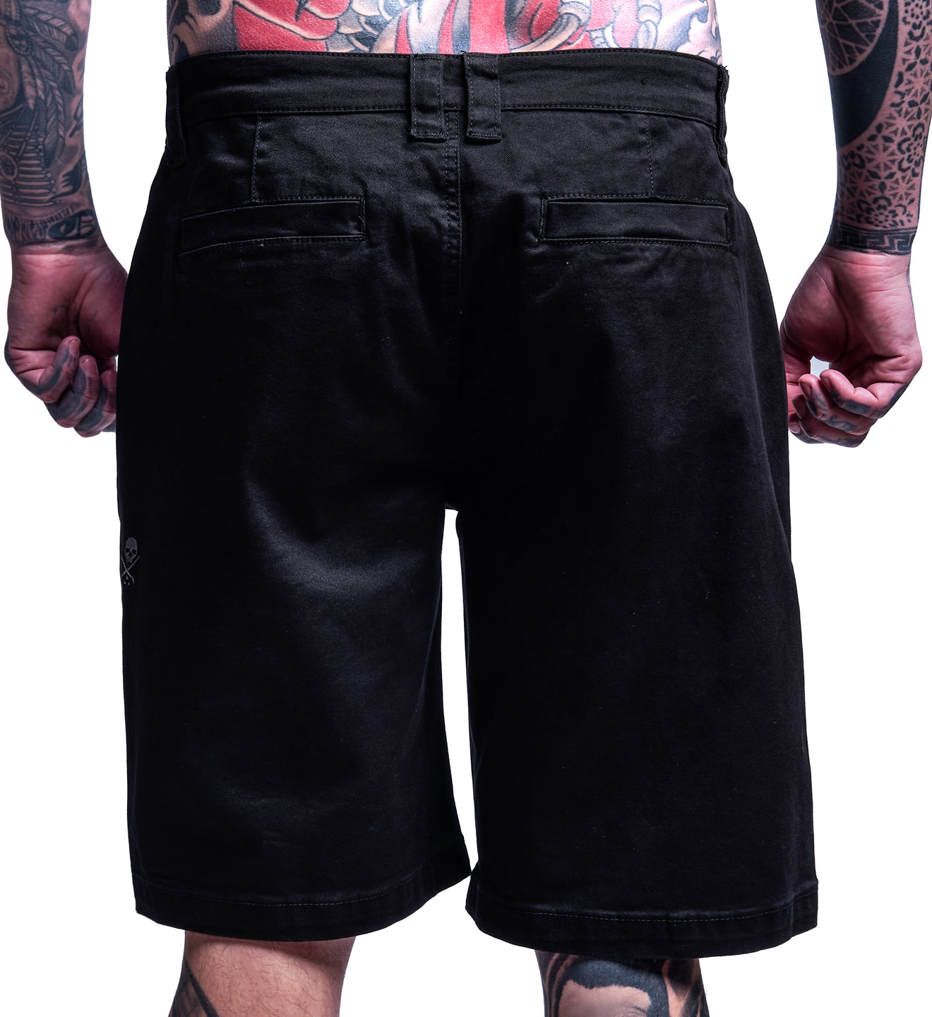 Black shorts worn by a person with tattoos on a white background