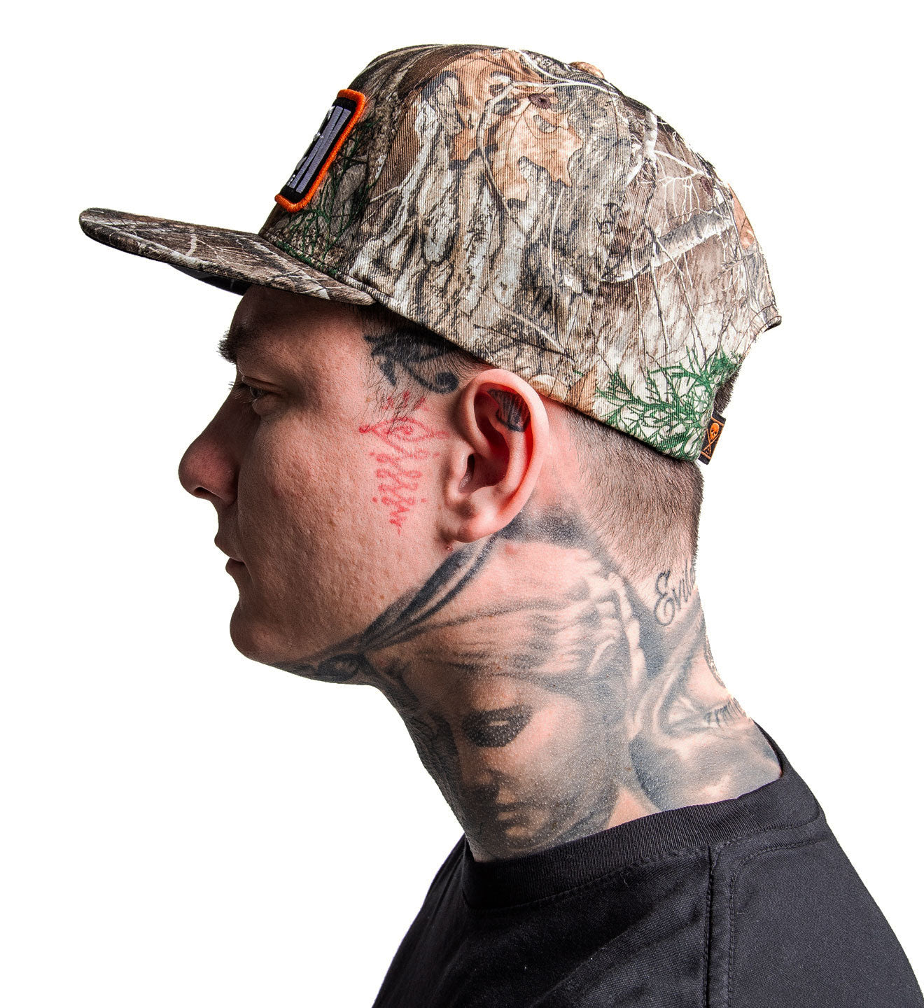 Man wearing a camouflage cap with tattoos on his neck and face against a white background