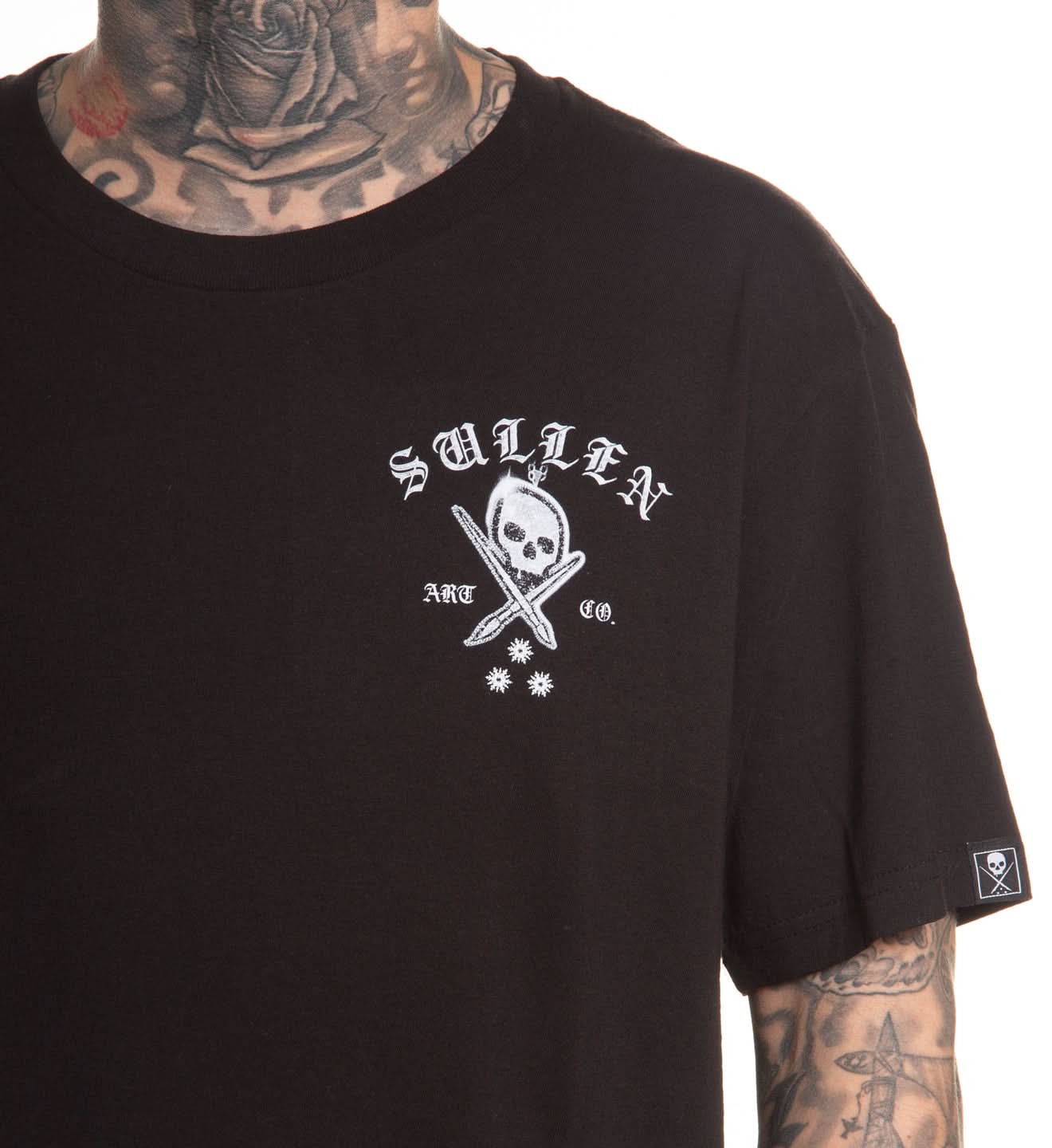 Black t-shirt with a white logo featuring a skull and sword, worn by a person with tattoos.