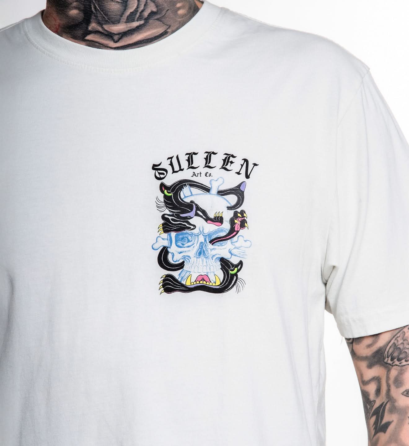 White t-shirt with a graphic design and 'Sullen' branding worn by a person.