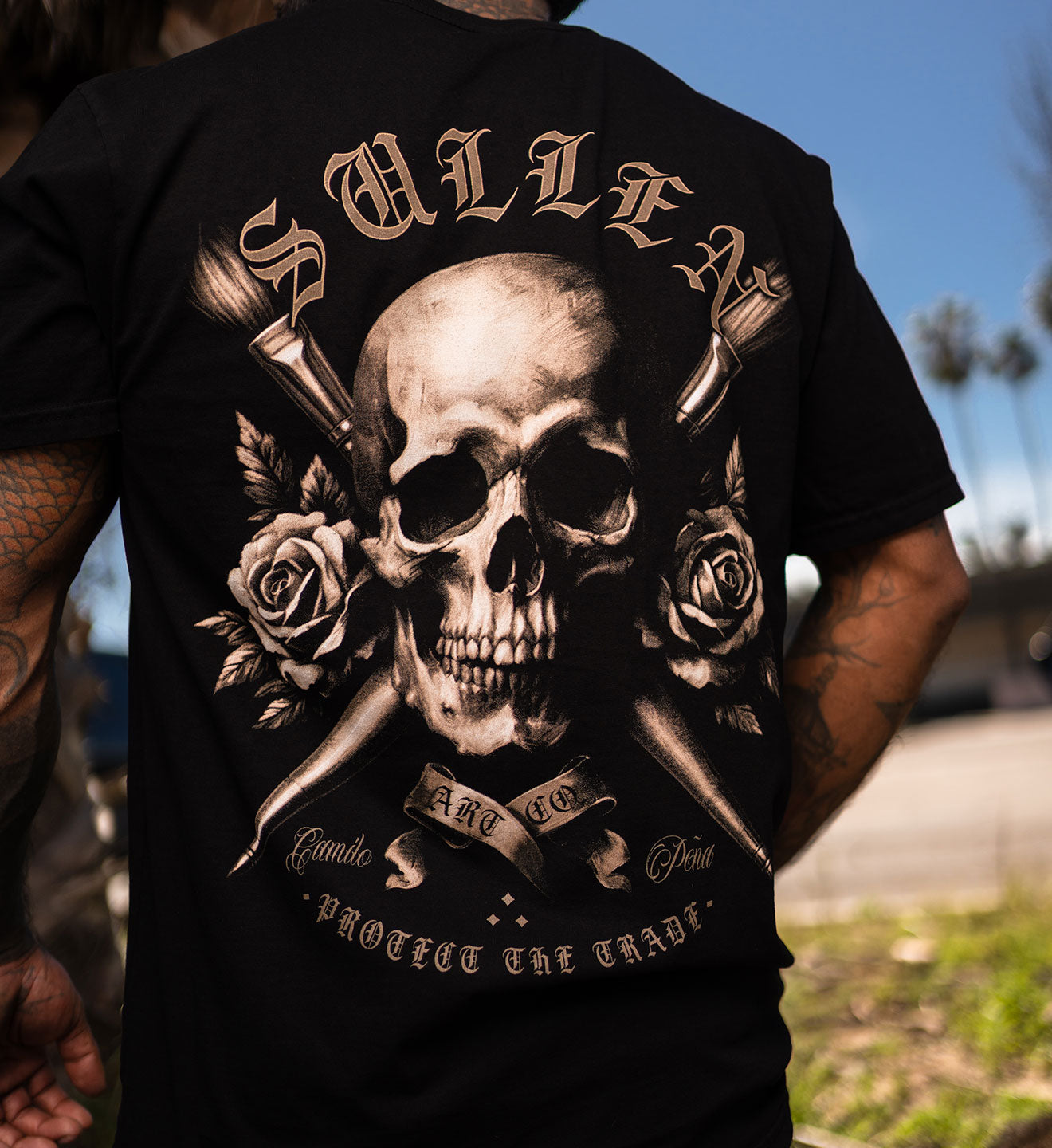 Person wearing a black t-shirt with a skull and roses design and 'Sullen' branding.