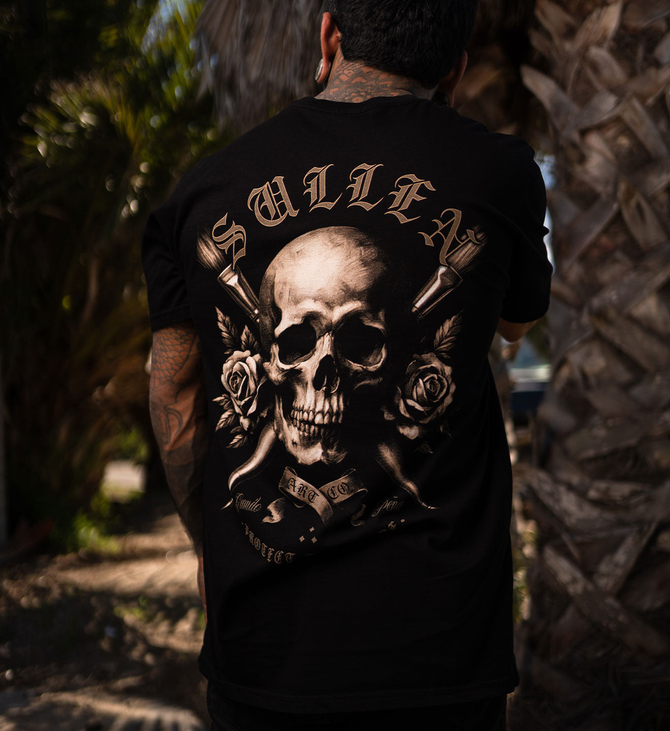 Person wearing a black t-shirt with a skull and crossbones design, standing outdoors.