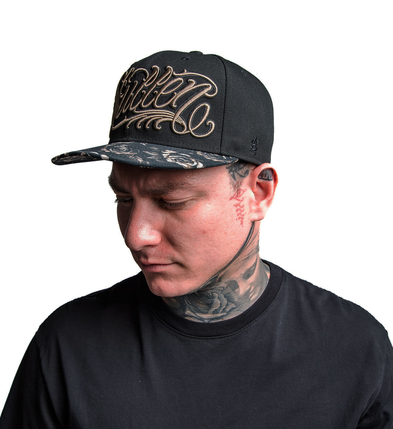 Man wearing a black cap with gold embroidery on a white background