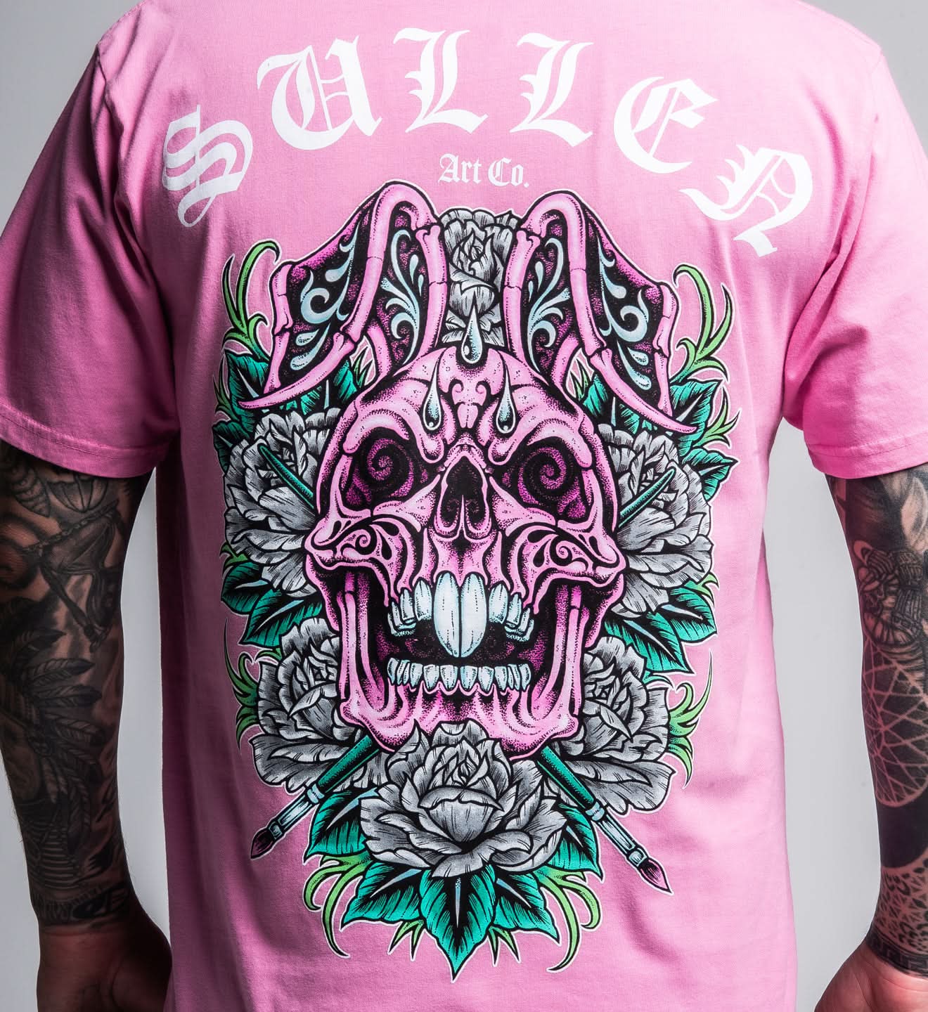 Pink t-shirt with a detailed skull and floral design, featuring the brand 'Sullen'.