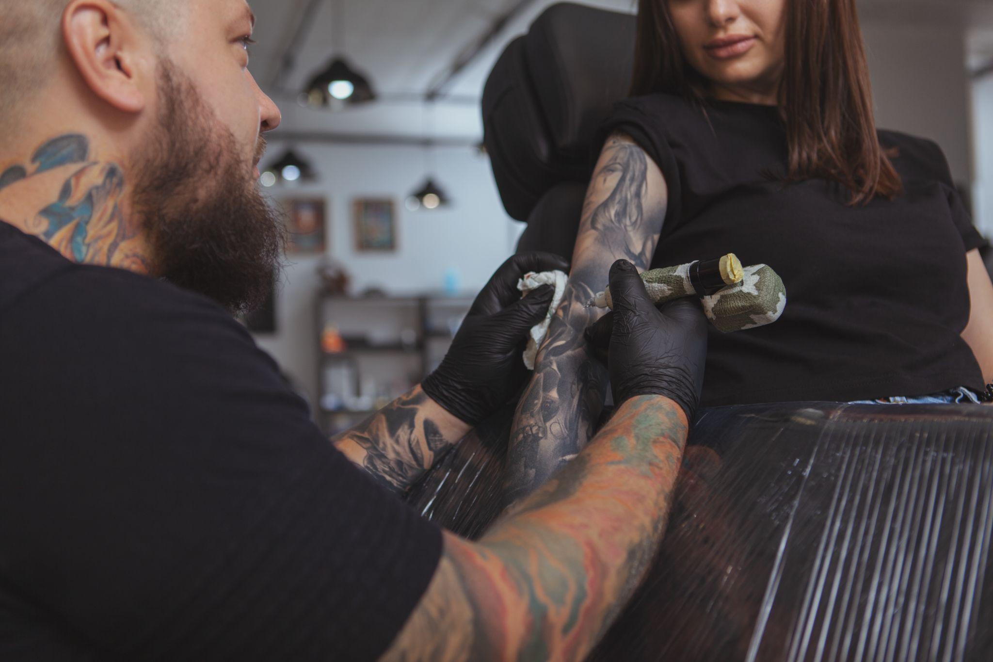 Woman getting painful tattoo near elbow