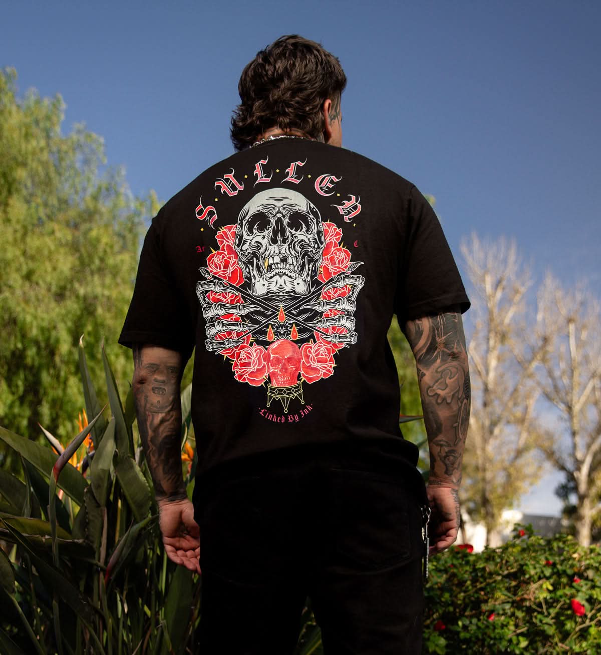 Person wearing a black t-shirt with a skull and roses design, standing outdoors.