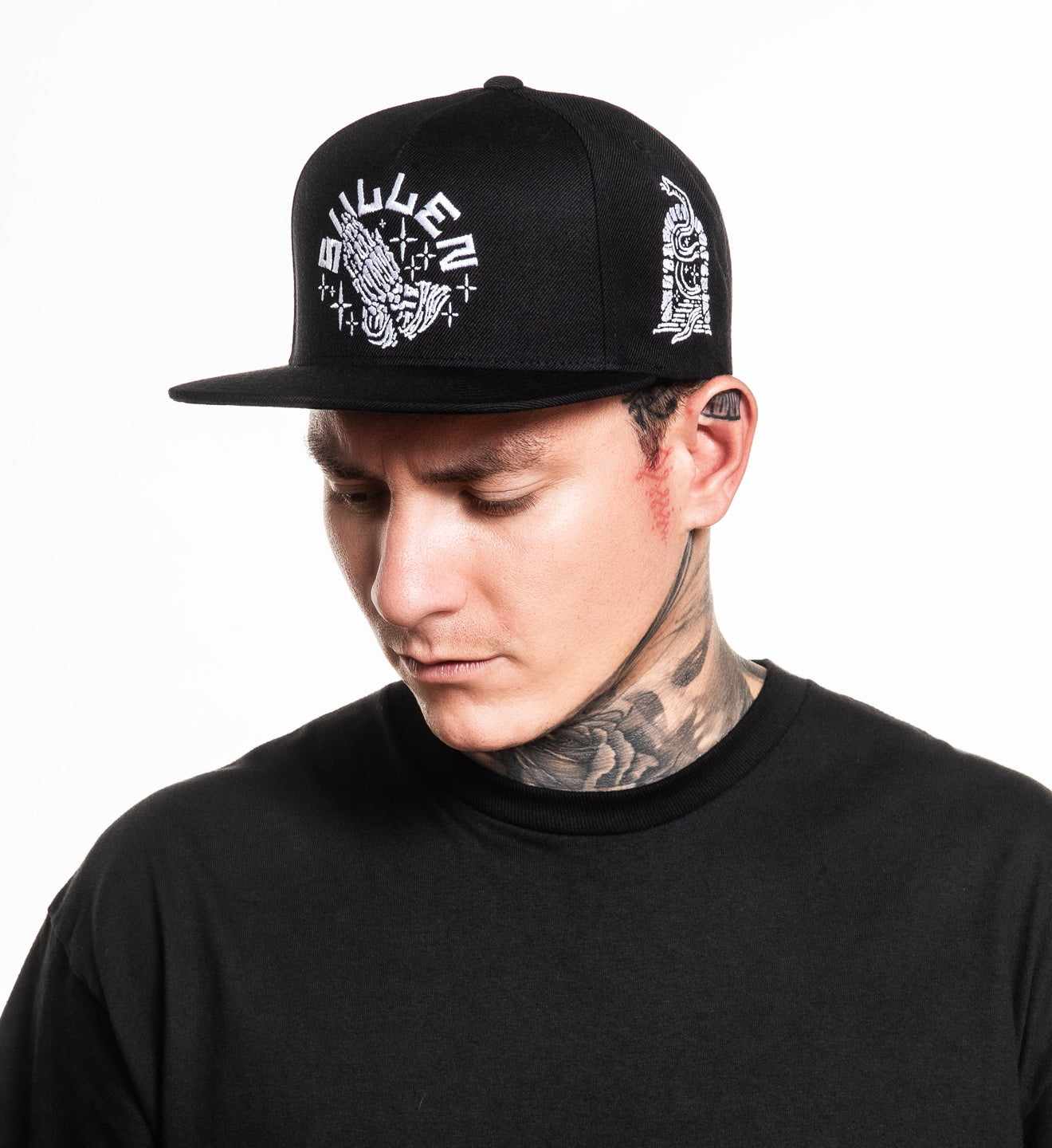 Man wearing a black cap with white designs on a white background
