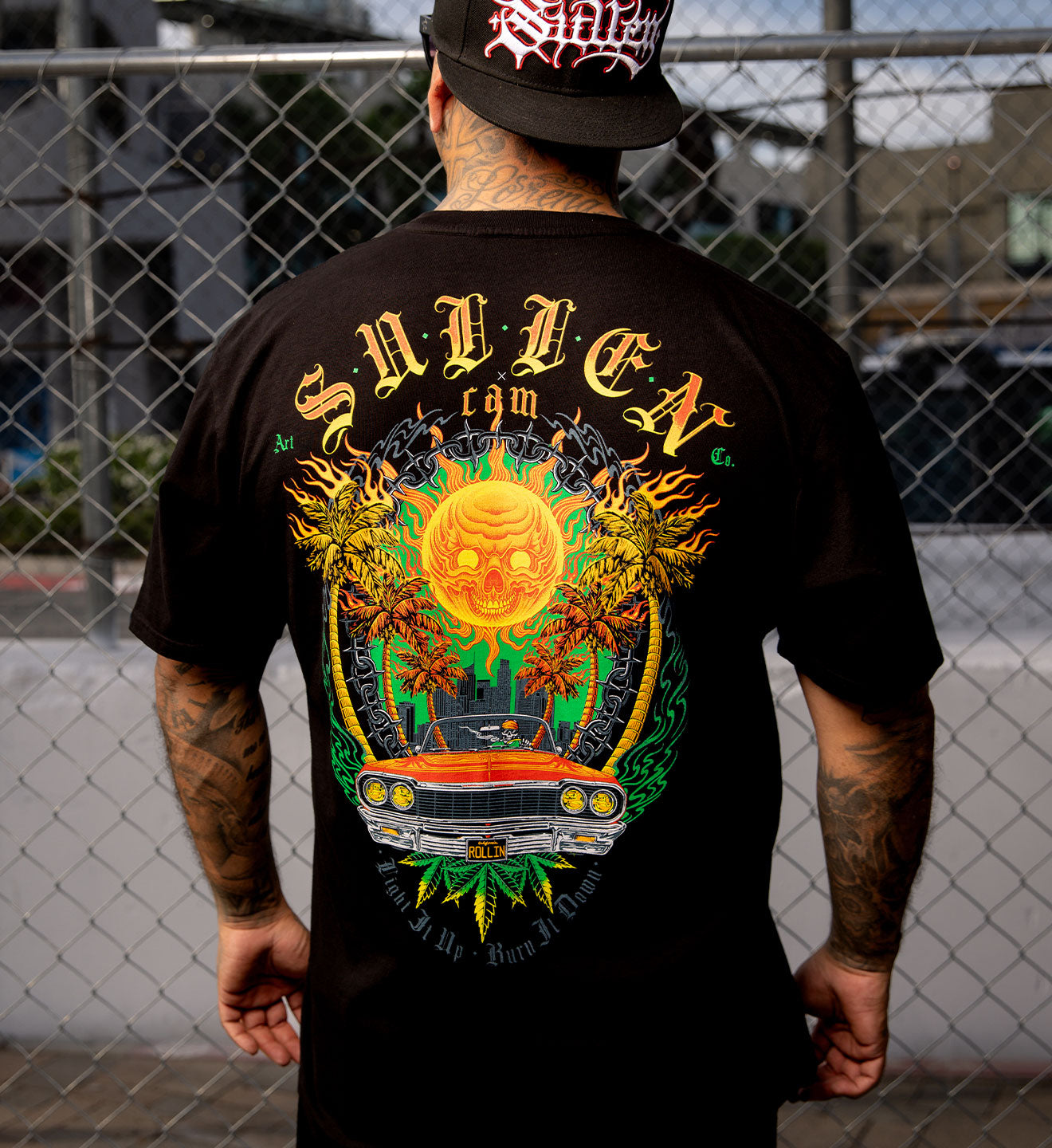 Person wearing a black t-shirt with colorful graphic design and 'Sullen' branding.